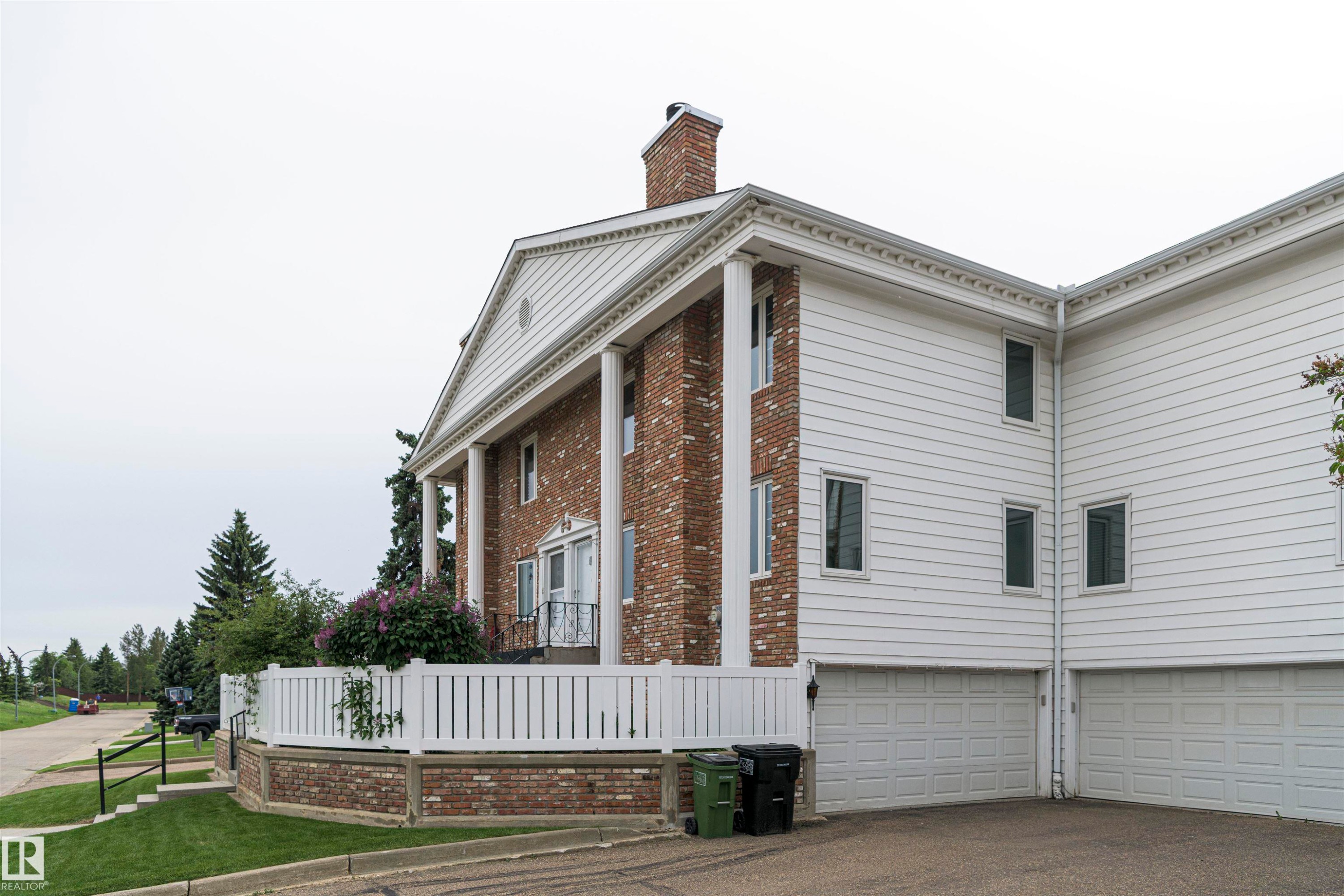 Brick and white siding exterior featuring a columned portico, gable roofline, and attached two-car garage - 5010 147 Street Nw, Edmonton, AB