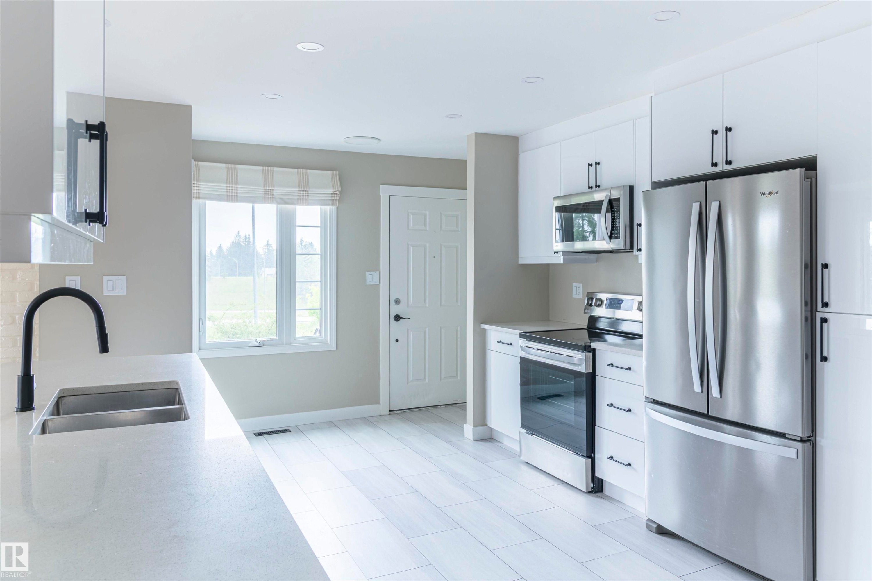 Modern kitchen featuring a stainless steel French door refrigerator, matching stainless steel range, and an over-range microwave - 5010 147 Street Nw, Edmonton, AB