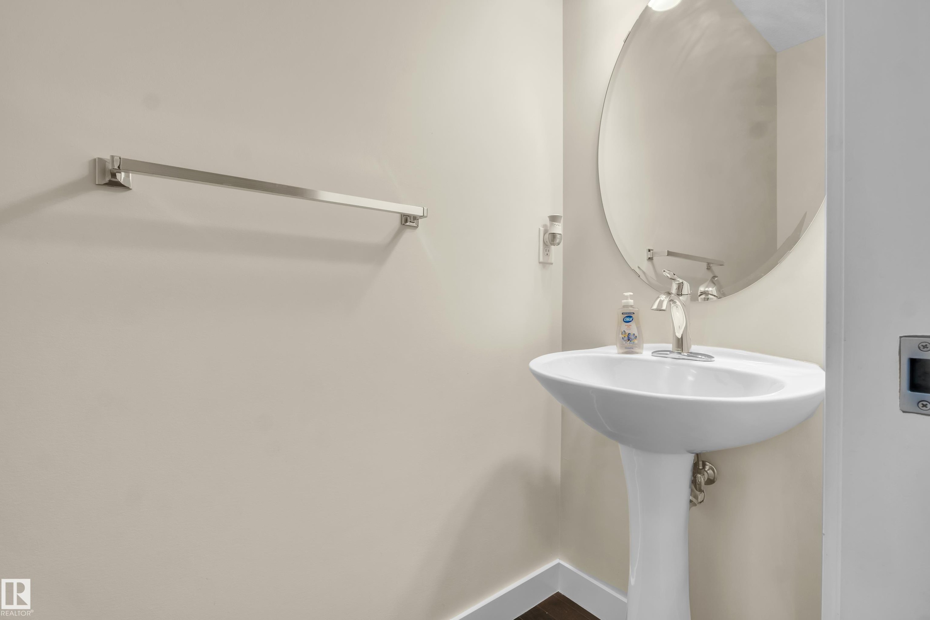 Pedestal sink with polished chrome faucet and round wall mirror - 3071 Carpenter Landing Sw, Edmonton, AB