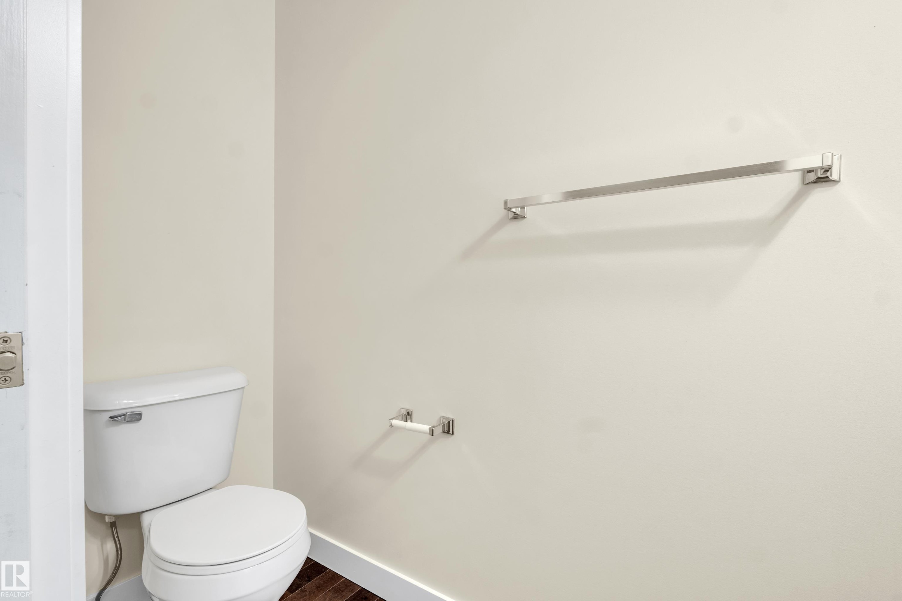 White toilet with a dual flush mechanism, wood-finish flooring, and light-toned wall paint - 3071 Carpenter Landing Sw, Edmonton, AB