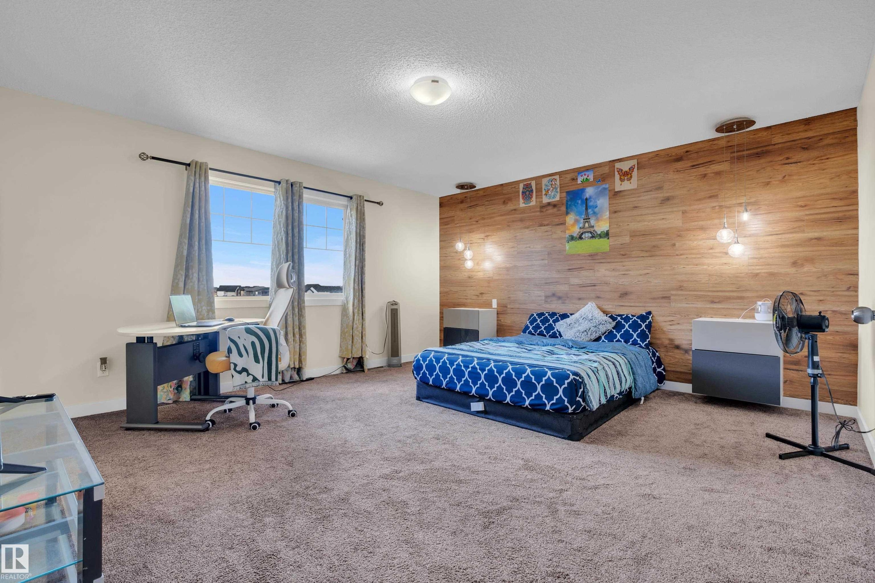 Spacious room featuring a prominent wood-panel accent wall with integrated pendant lighting - 3071 Carpenter Landing Sw, Edmonton, AB