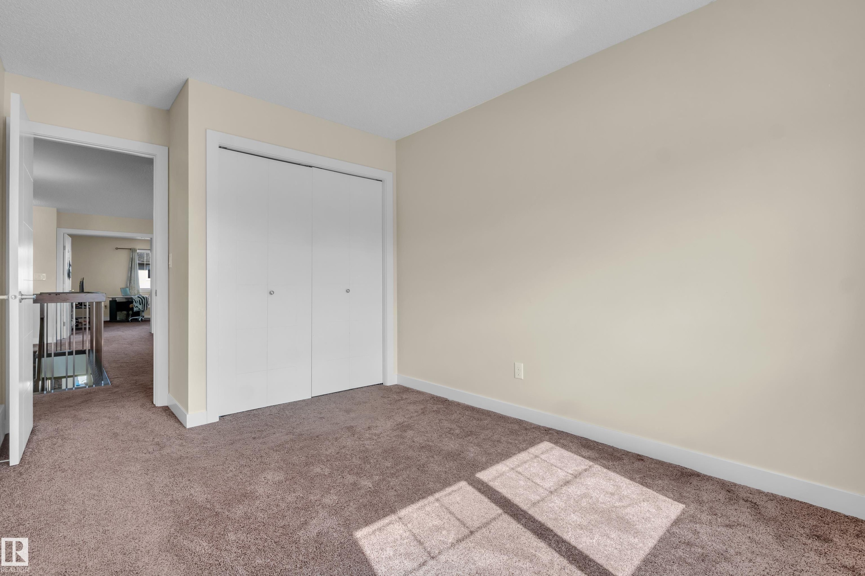 Neutral tone walls with white trim, brown carpeting, and a built-in closet with white bifold doors - 3071 Carpenter Landing Sw, Edmonton, AB
