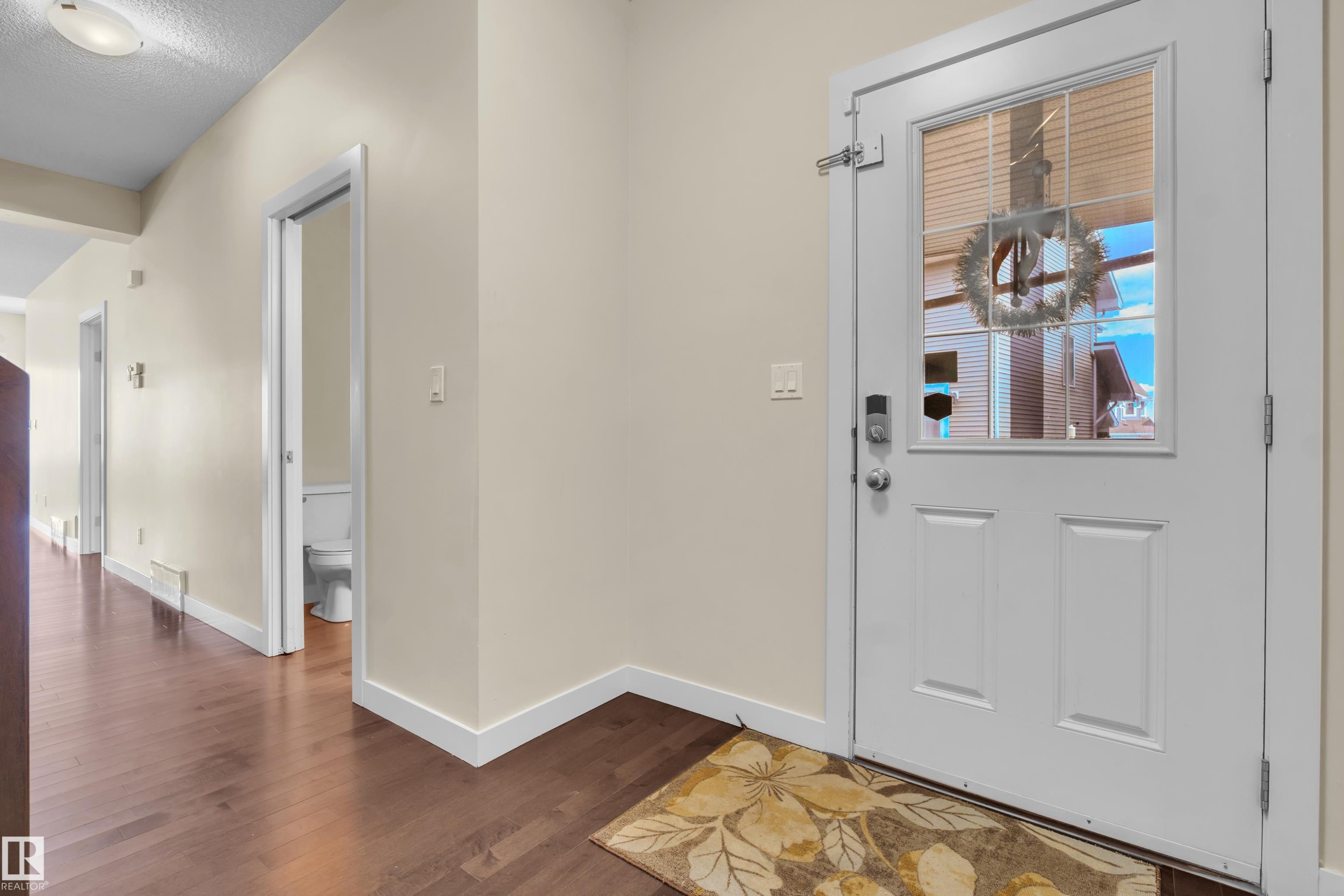 Entryway featuring a paneled door with integrated window, dark wood-finish flooring, and light-toned walls - 3071 Carpenter Landing Sw, Edmonton, AB