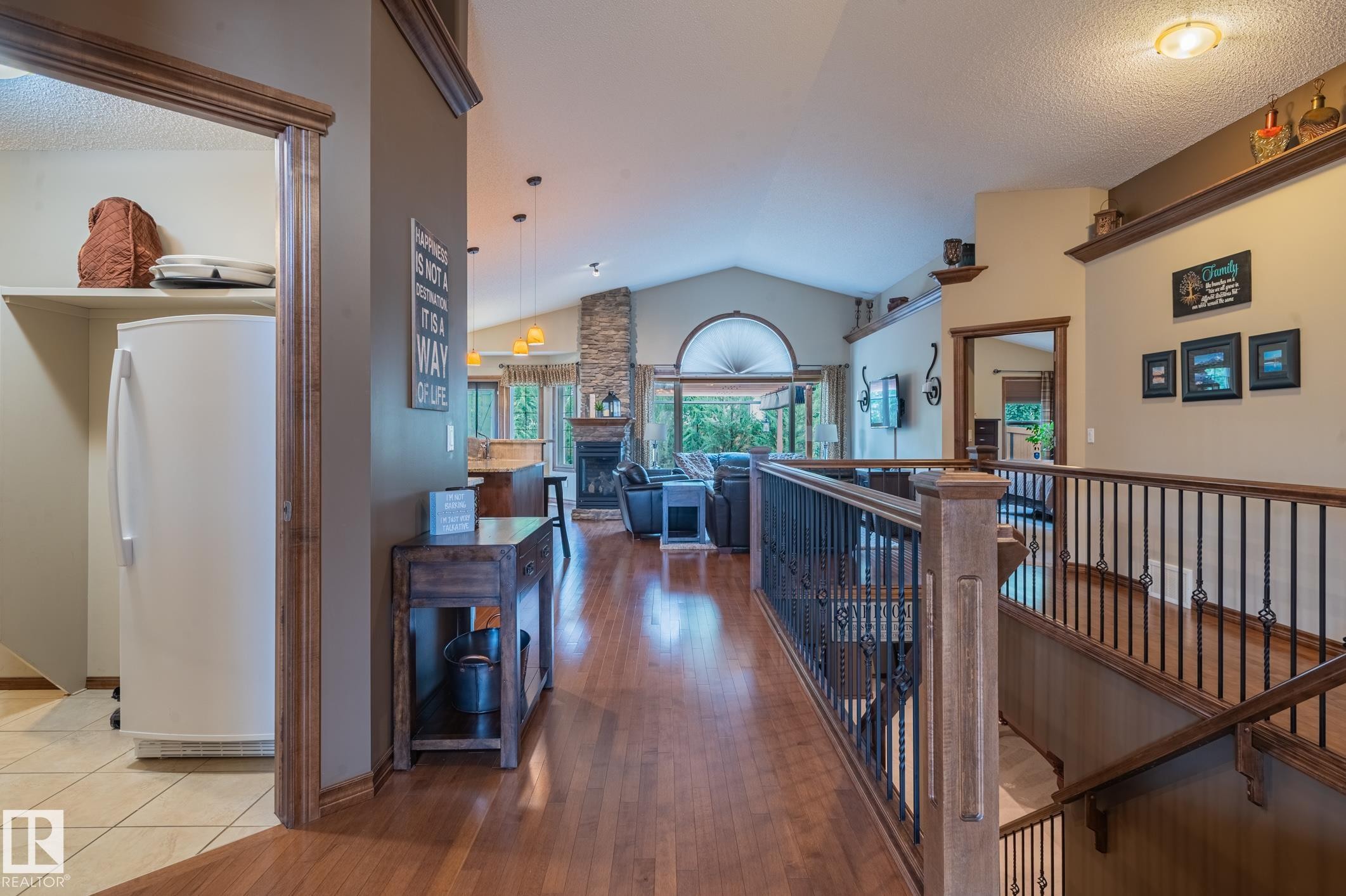 Expansive interior featuring rich wood-finish flooring, a vaulted ceiling, and a stone-clad fireplace - 19 Newton Place, St. Albert, AB