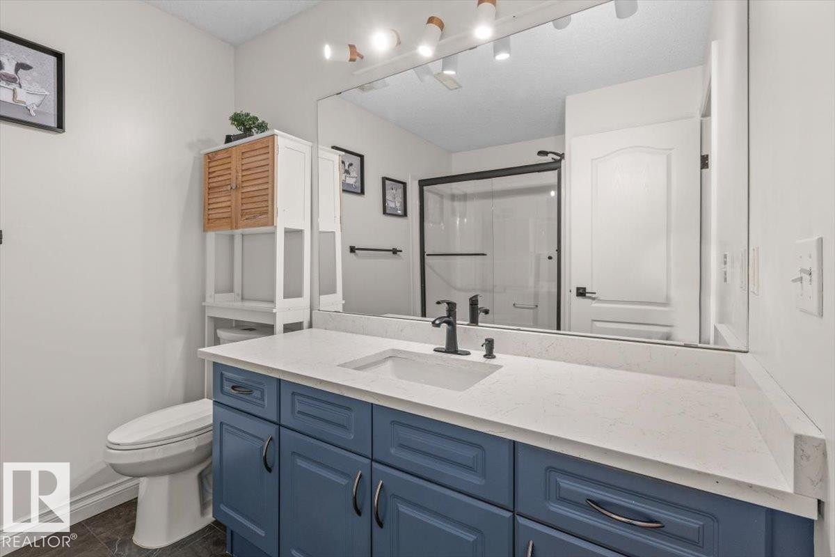 Blue vanity with an integrated sink, polished countertop, and matte black faucet - 15420 44 Street Nw, Edmonton, AB