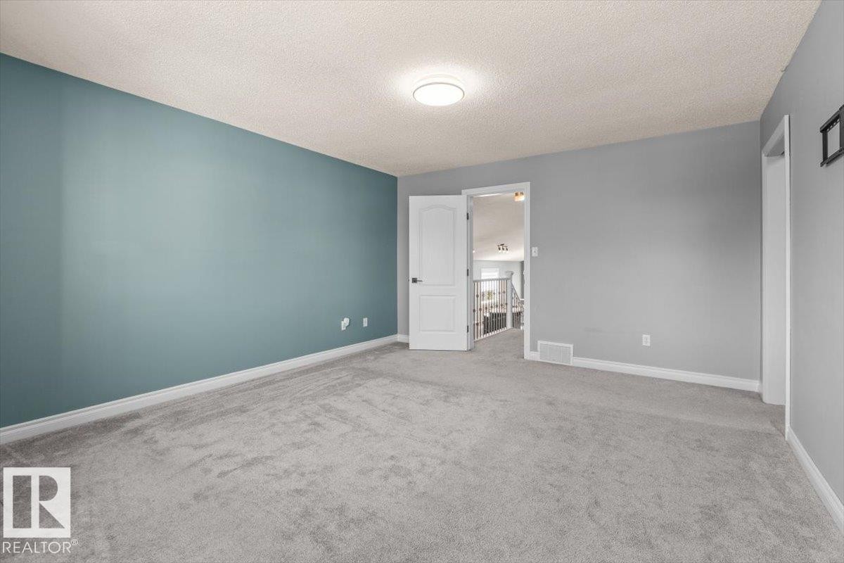 Plush gray carpeting with contrasting wall colors and a flush-mount ceiling light fixture - 15420 44 Street Nw, Edmonton, AB