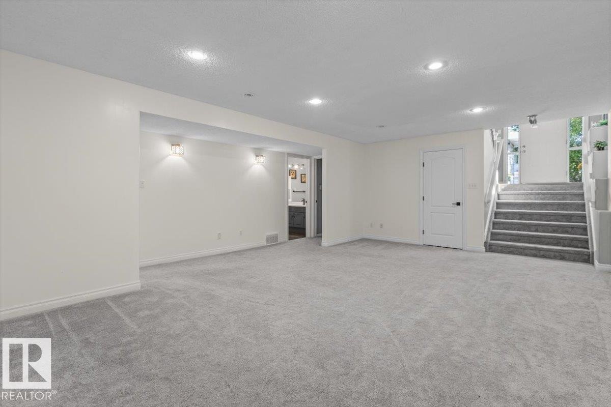Carpeted lower level with recessed lighting, wall sconces, and interior staircase - 15420 44 Street Nw, Edmonton, AB