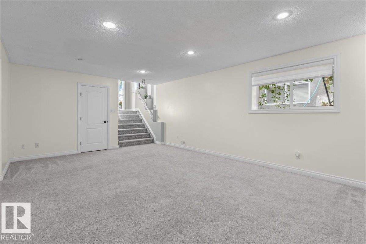 Spacious room with light gray carpeting, recessed ceiling lighting, a white interior door, and a multi-pane window - 15420 44 Street Nw, Edmonton, AB