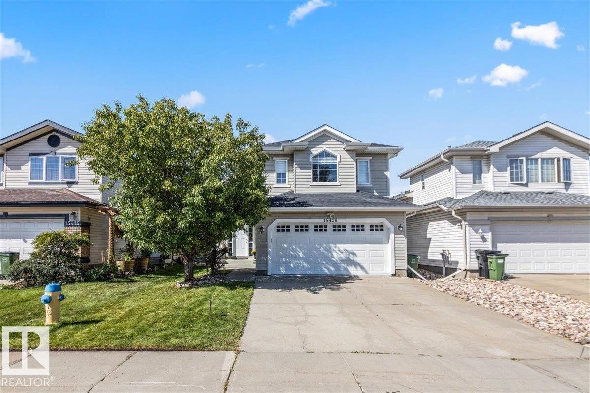 Two-story residence featuring light gray siding, a two-car garage, and an arched window - 15420 44 Street Nw, Edmonton, AB