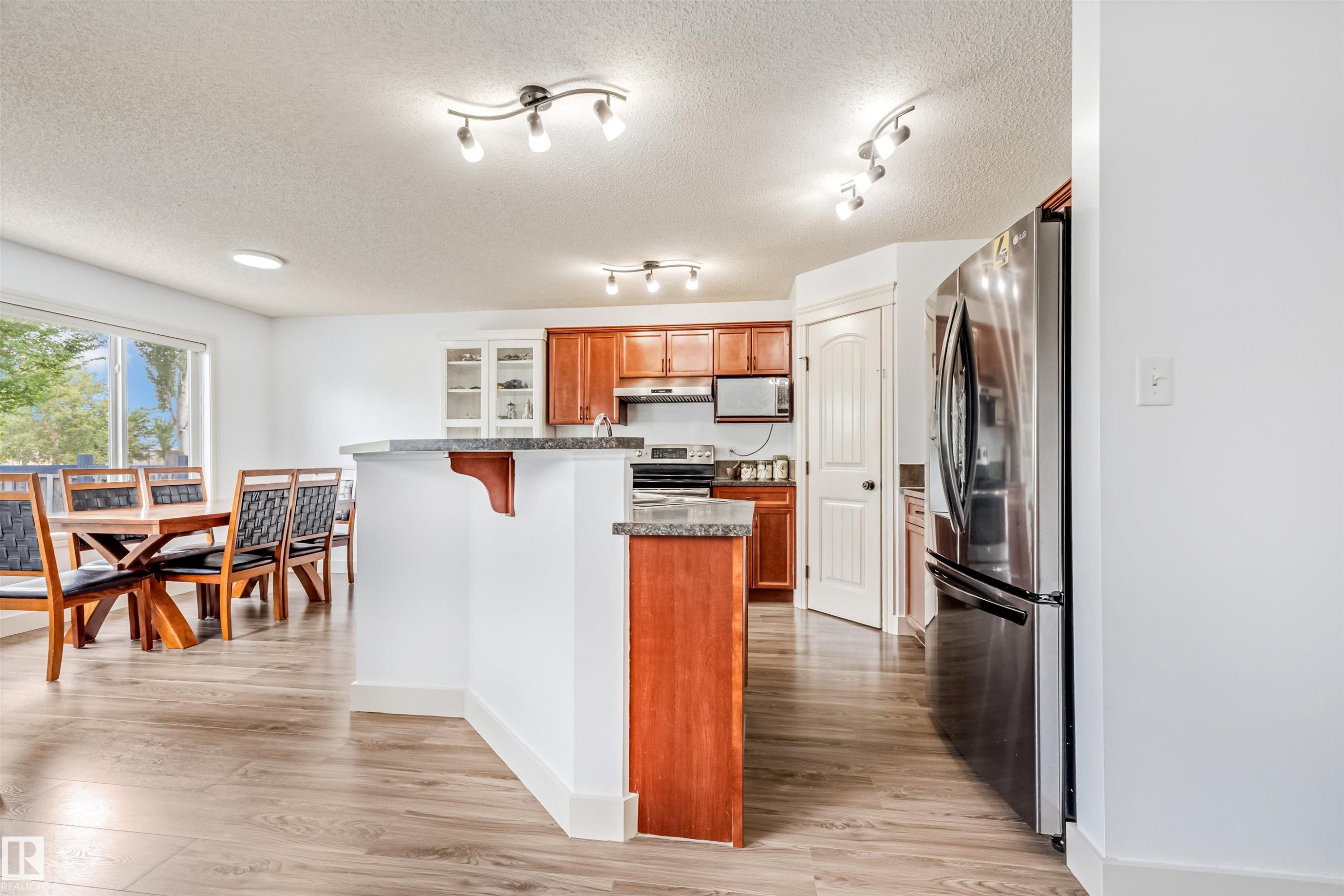 Wood-finish flooring, white walls, and a kitchen island with stone countertops - 20324 48 Avenue Nw, Edmonton, AB