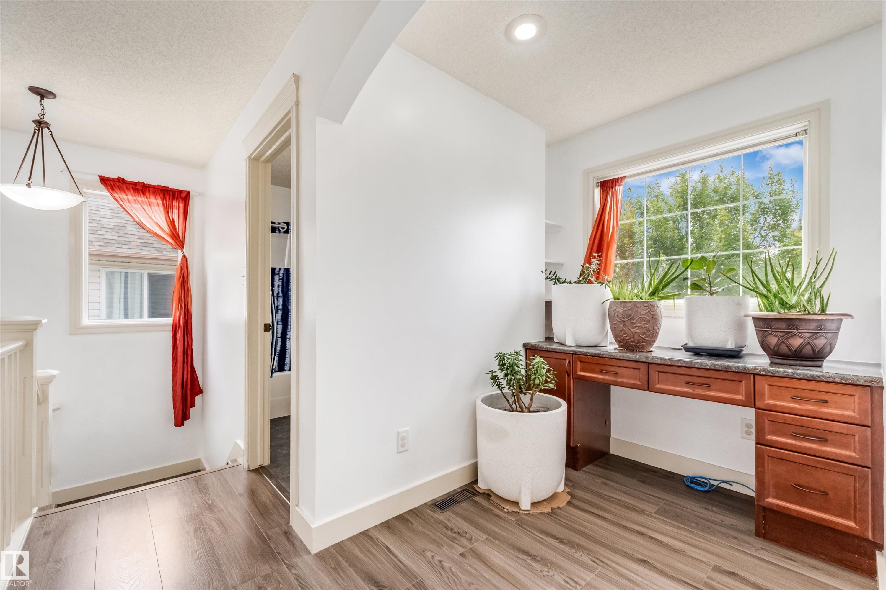 Wood-finish flooring, recessed lighting, built-in desk with cabinet storage, window with exterior scenery, and a ceiling-mounted light fixture - 20324 48 Avenue Nw, Edmonton, AB