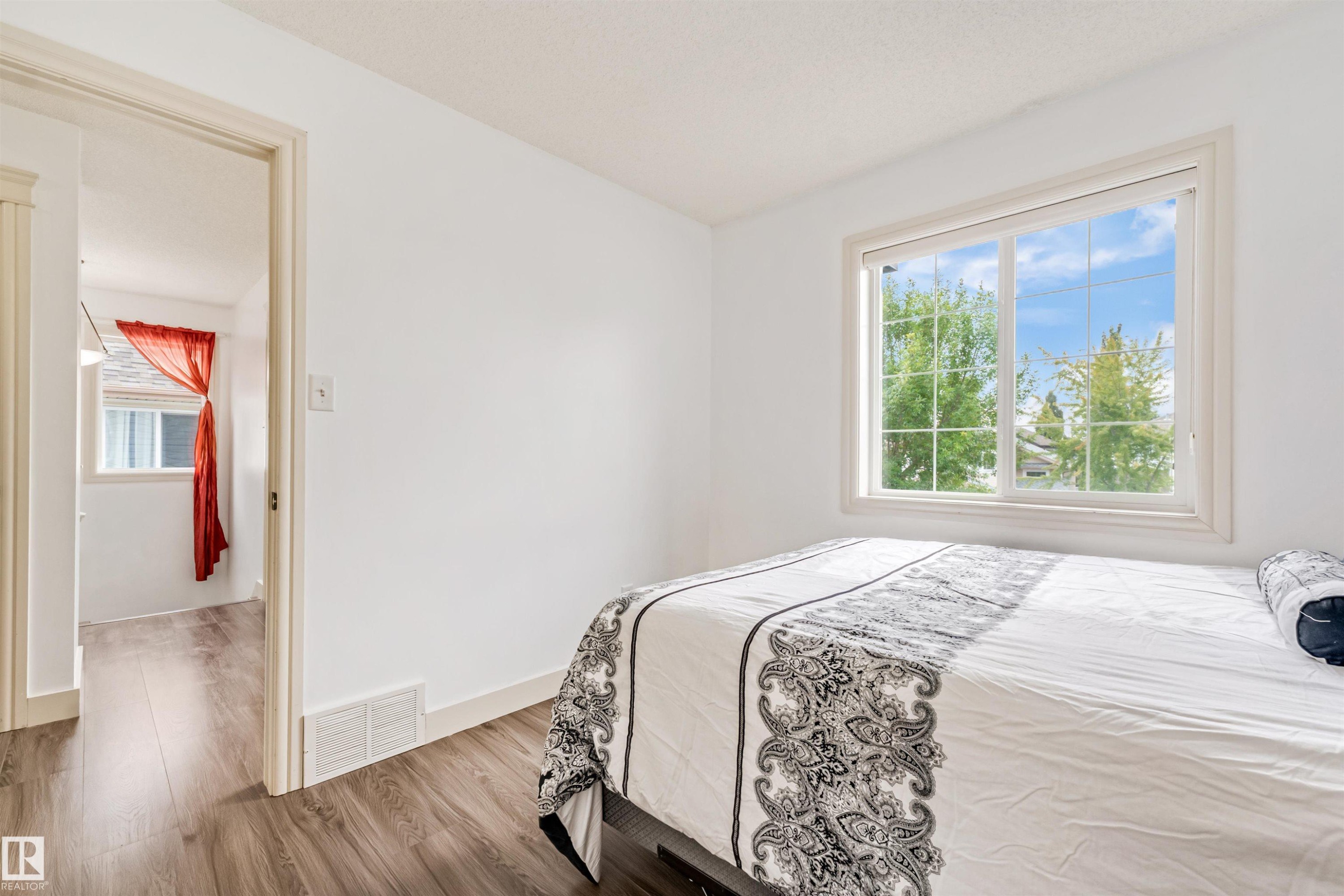 White painted walls, wood-finish flooring, and a large window with grid panes - 20324 48 Avenue Nw, Edmonton, AB