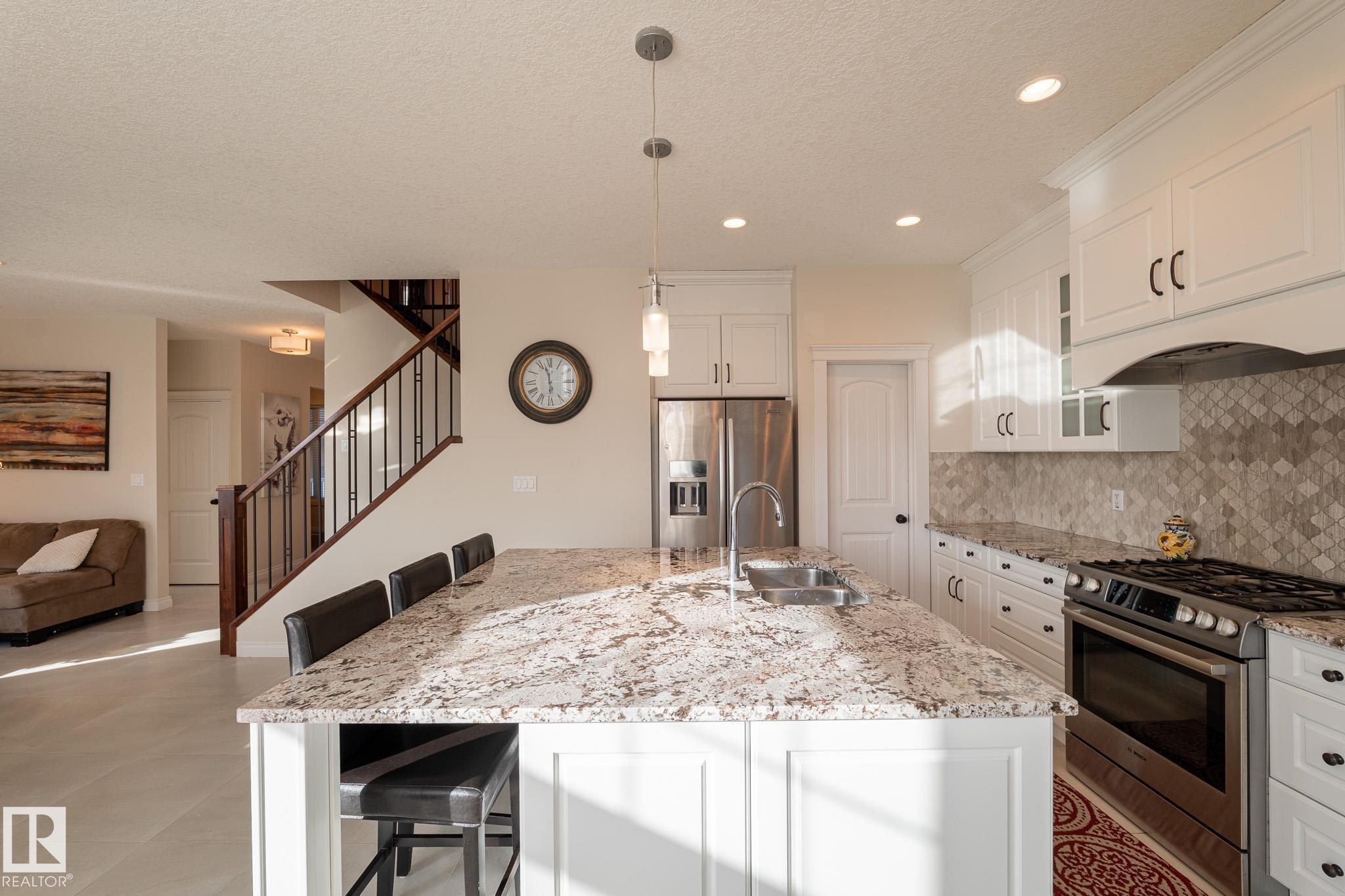Kitchen featuring white cabinetry, stainless steel appliances, granite countertops, and a tiled backsplash - 914 Crystallina Nera Way Nw, Edmonton, AB