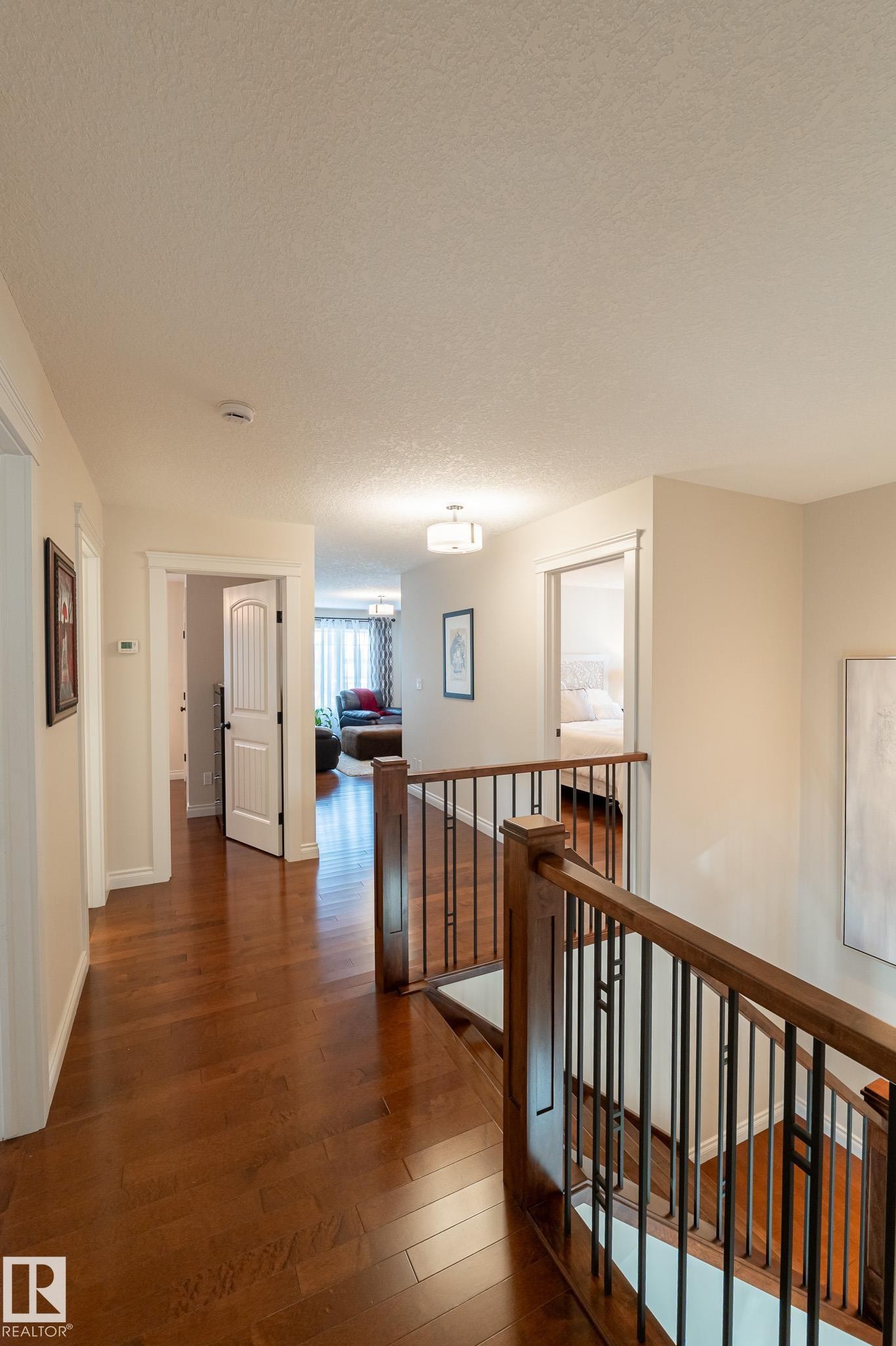 Hardwood flooring, wood railing with metal balusters, and overhead lighting - 914 Crystallina Nera Way Nw, Edmonton, AB