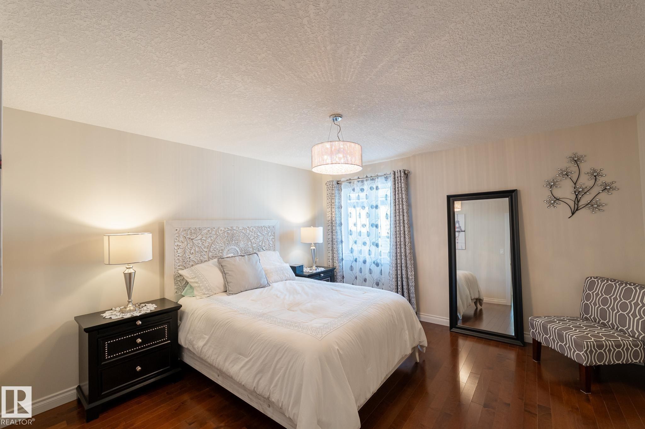 Wood-finish flooring, patterned accent wall, and a drum pendant light fixture - 914 Crystallina Nera Way Nw, Edmonton, AB