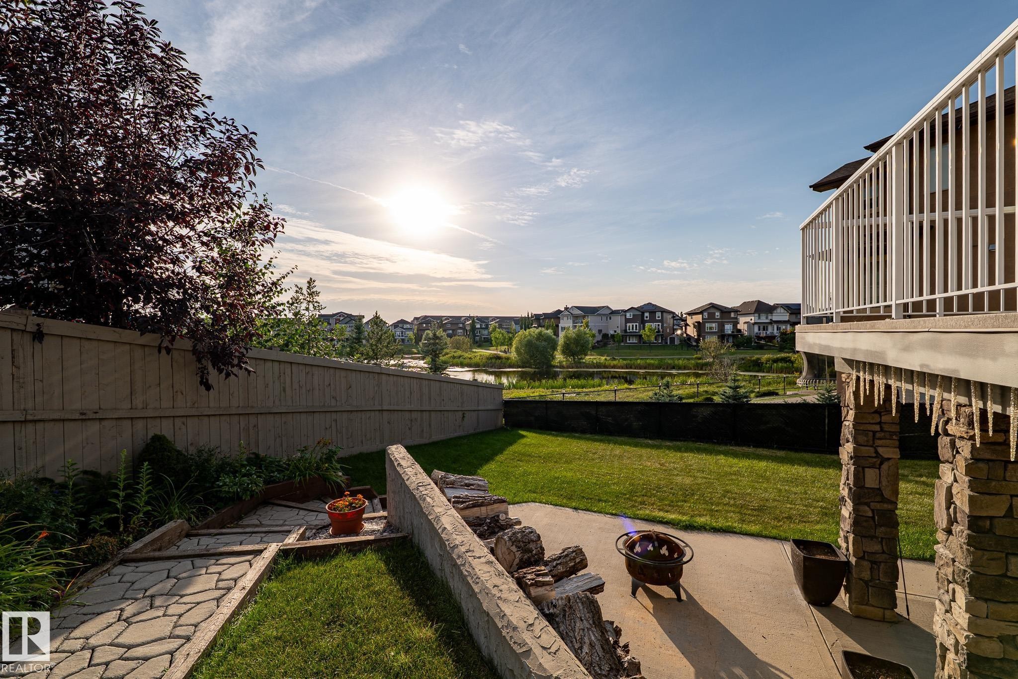 Expansive backyard featuring a stone patio, manicured lawn, and a stone-clad support pillar - 914 Crystallina Nera Way Nw, Edmonton, AB