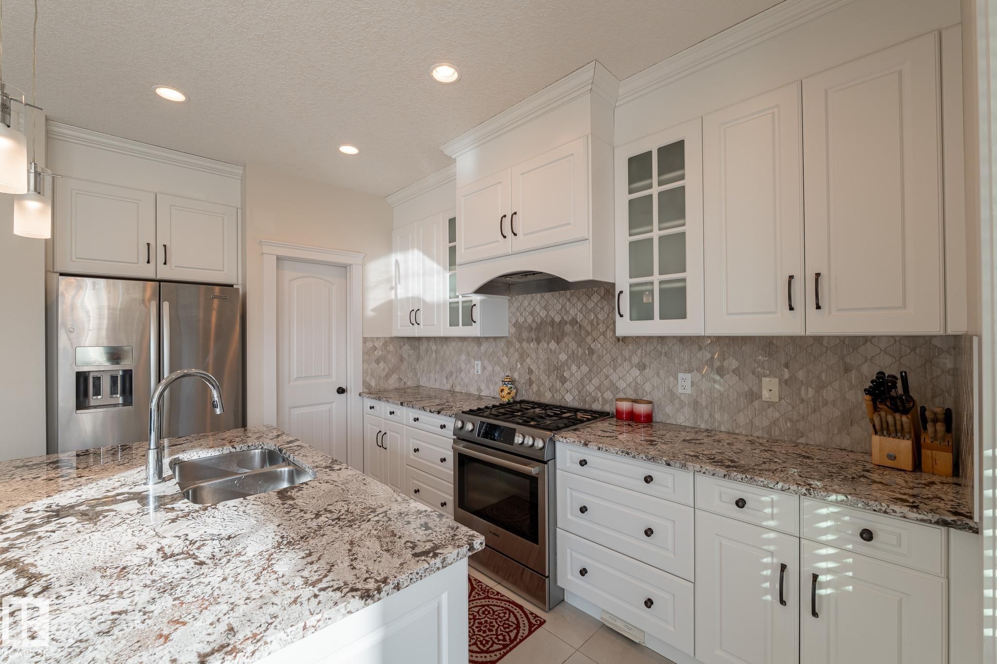Kitchen featuring white cabinetry, granite countertops, stainless steel appliances, a tiled backsplash, and recessed lighting - 914 Crystallina Nera Way Nw, Edmonton, AB