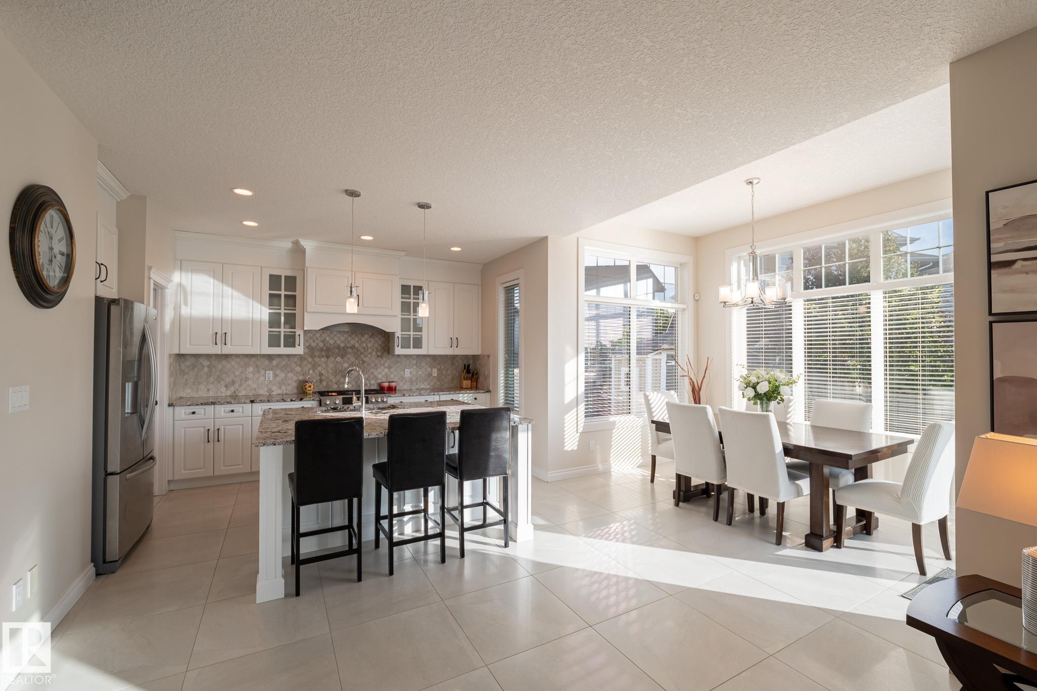 Kitchen featuring white cabinetry, stainless steel appliances, granite countertops, and a tile backsplash - 914 Crystallina Nera Way Nw, Edmonton, AB