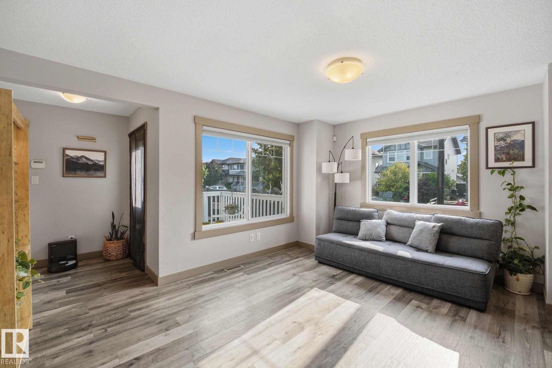 Spacious living area featuring neutral wall tones, and two large windows - 17621 10 Avenue Sw, Edmonton, AB - Indoor Photo Showing Living Room