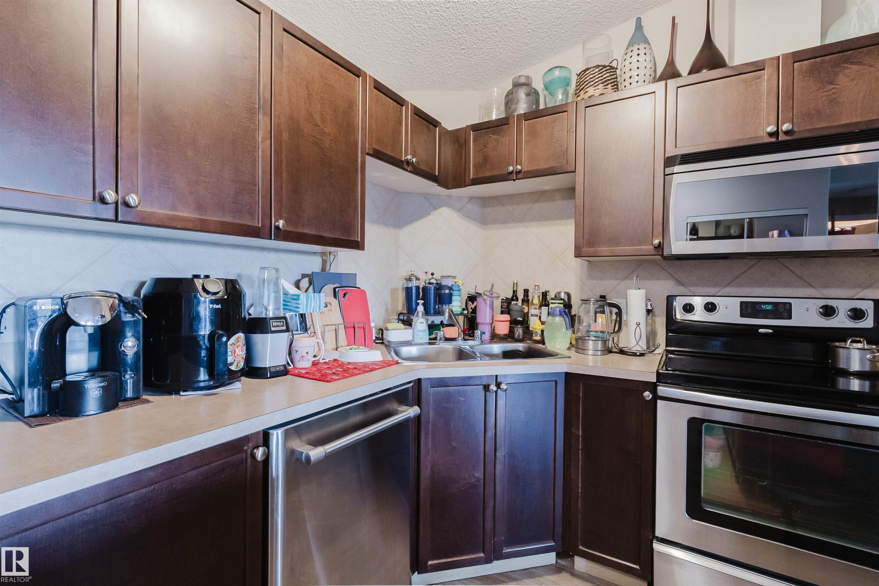 Rich wood-finish cabinetry, stainless steel appliances, durable laminate countertops, and a double basin sink - #7428 7327 South Terwillegar Dr Nw, Edmonton, AB