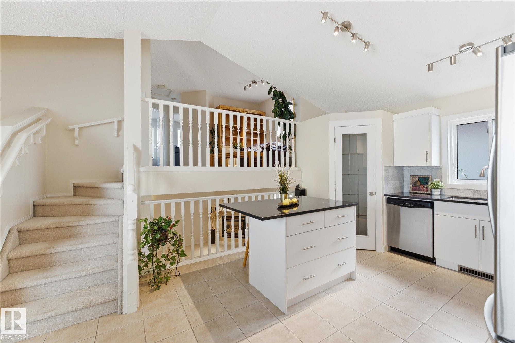 Kitchen featuring white cabinetry, stainless steel appliances, a center island with a dark countertop, and tile flooring - 1709 Turvey Bend Bend Nw, Edmonton, AB