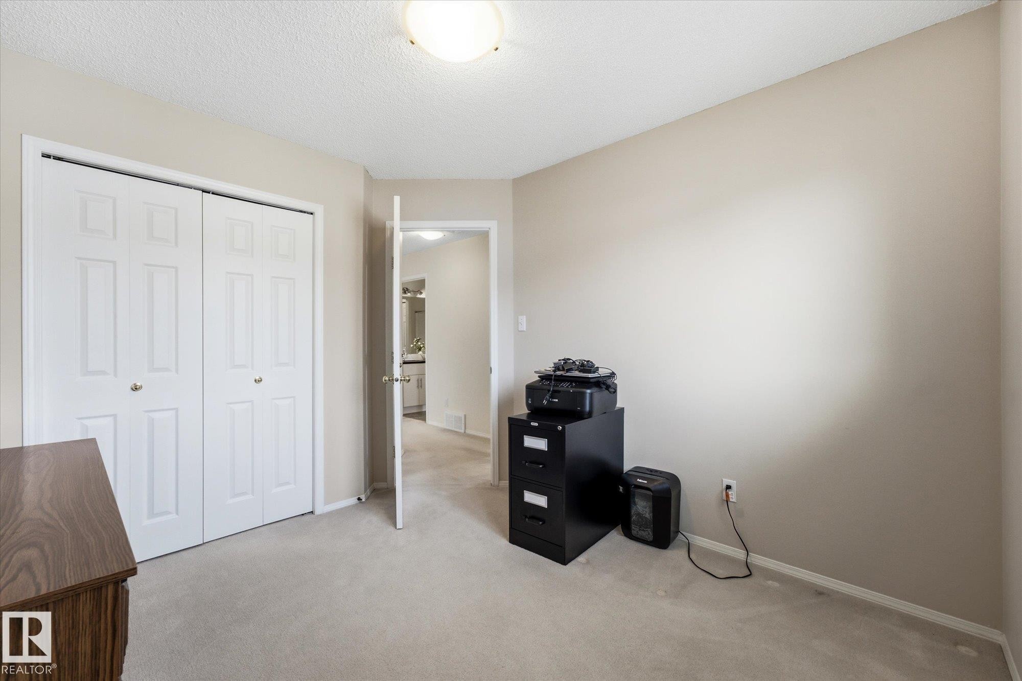 Neutral tone wall paint, flush mount ceiling light, white bi-fold closet doors, and light-toned carpet flooring - 1709 Turvey Bend Bend Nw, Edmonton, AB