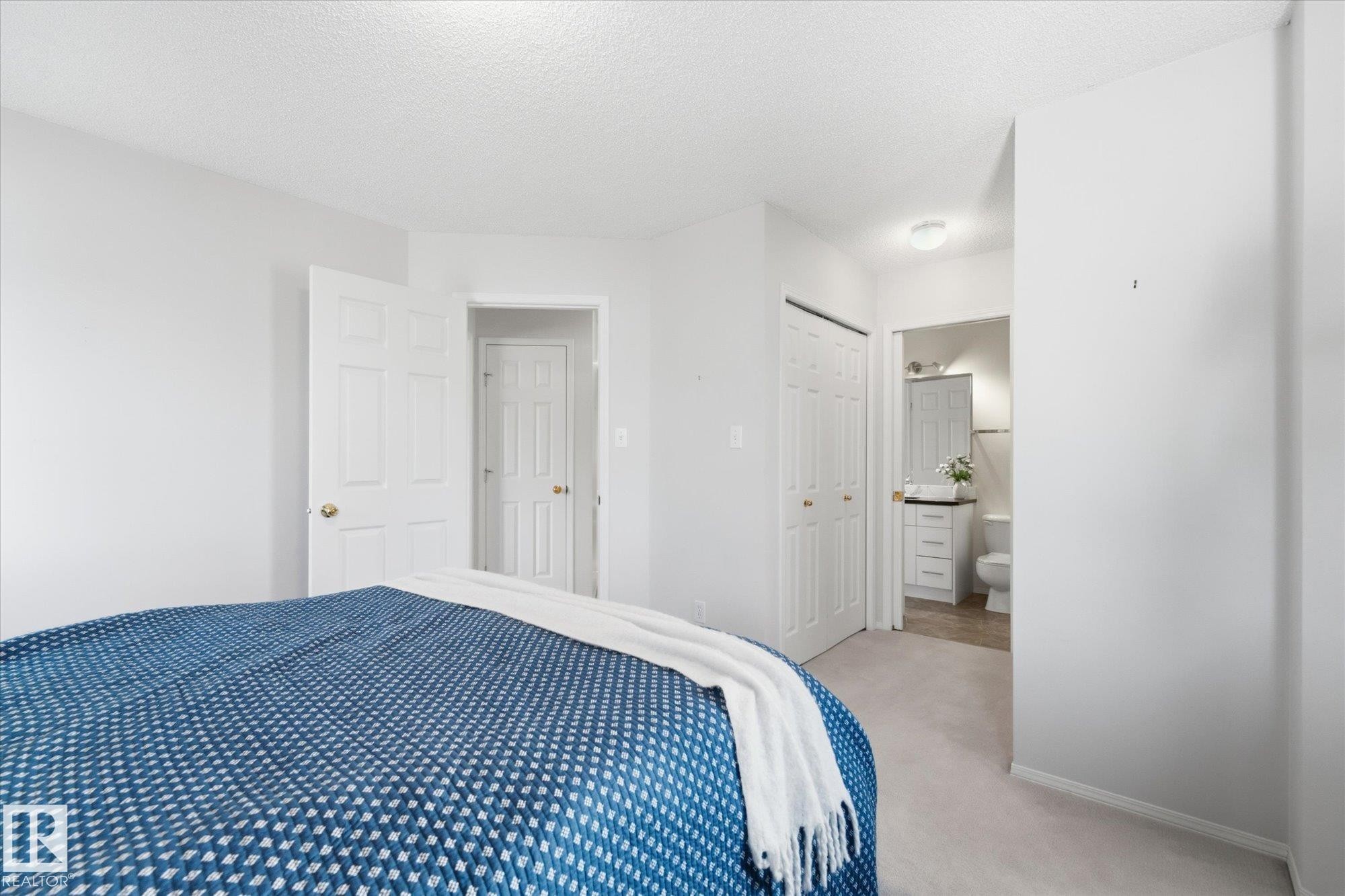 Carpeted bedroom with white walls, two panel doors, and a bi-fold closet door - 1709 Turvey Bend Bend Nw, Edmonton, AB