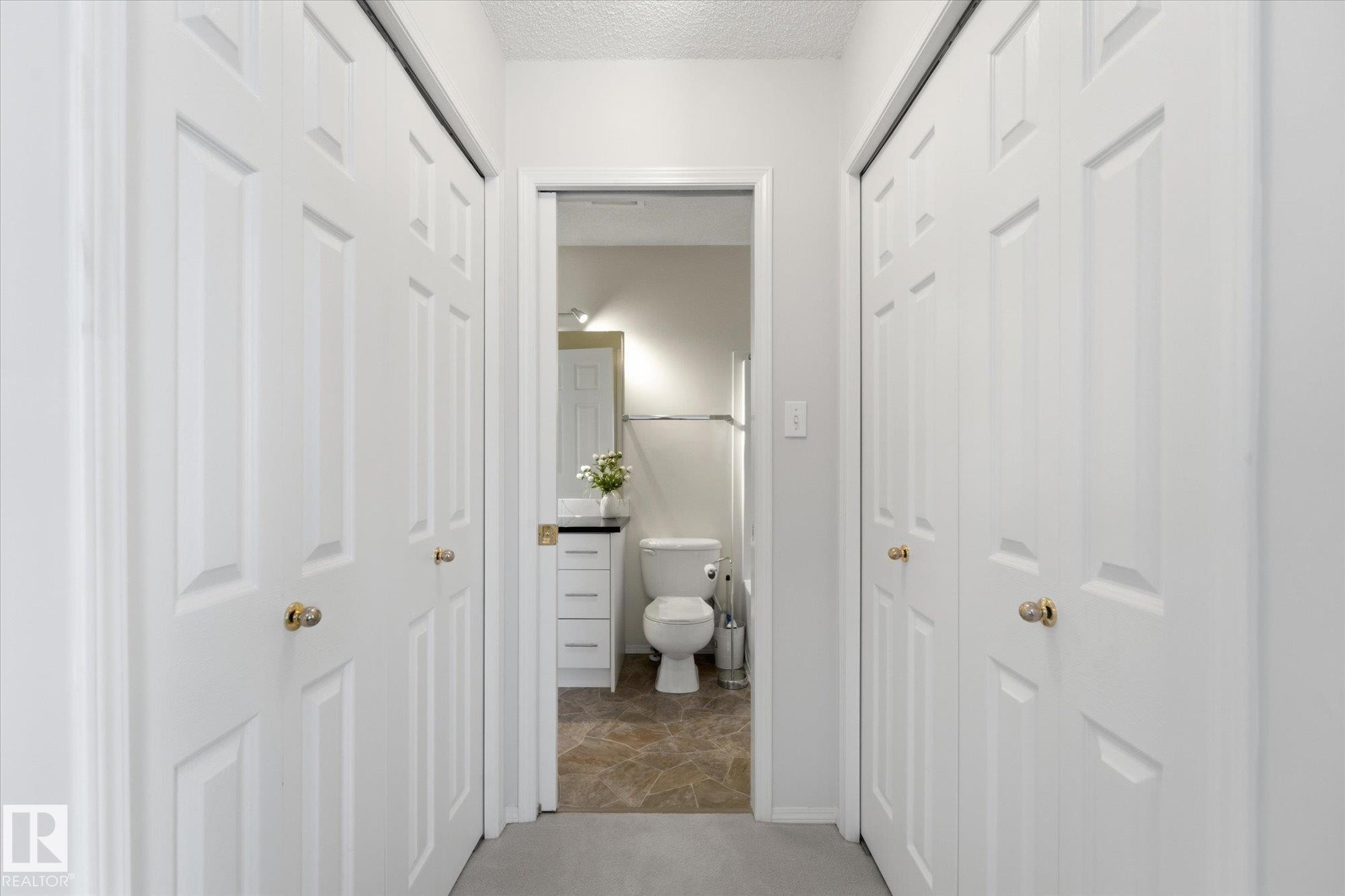 Hallway with carpet flooring, white paneled doors, and brass hardware - 1709 Turvey Bend Bend Nw, Edmonton, AB