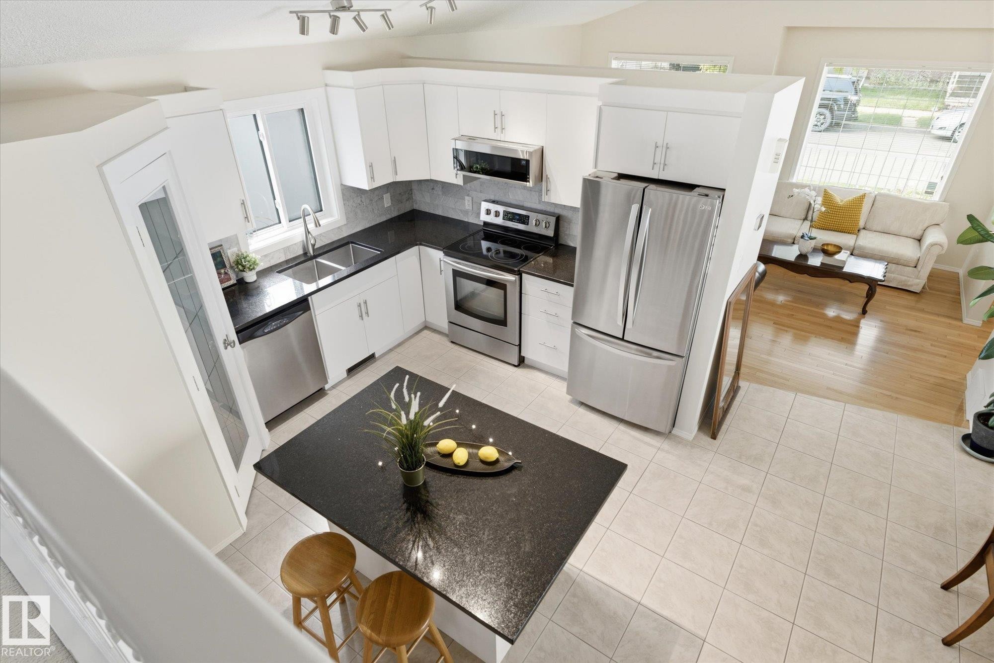 Bright kitchen featuring white cabinetry, stainless steel appliances, dark countertops, and tile flooring - 1709 Turvey Bend Bend Nw, Edmonton, AB