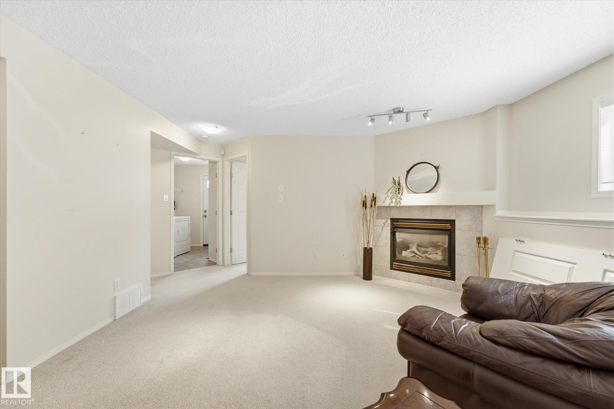 Corner fireplace with a tile surround and mantle, recessed lighting, and soft neutral carpeting - 1709 Turvey Bend Bend Nw, Edmonton, AB