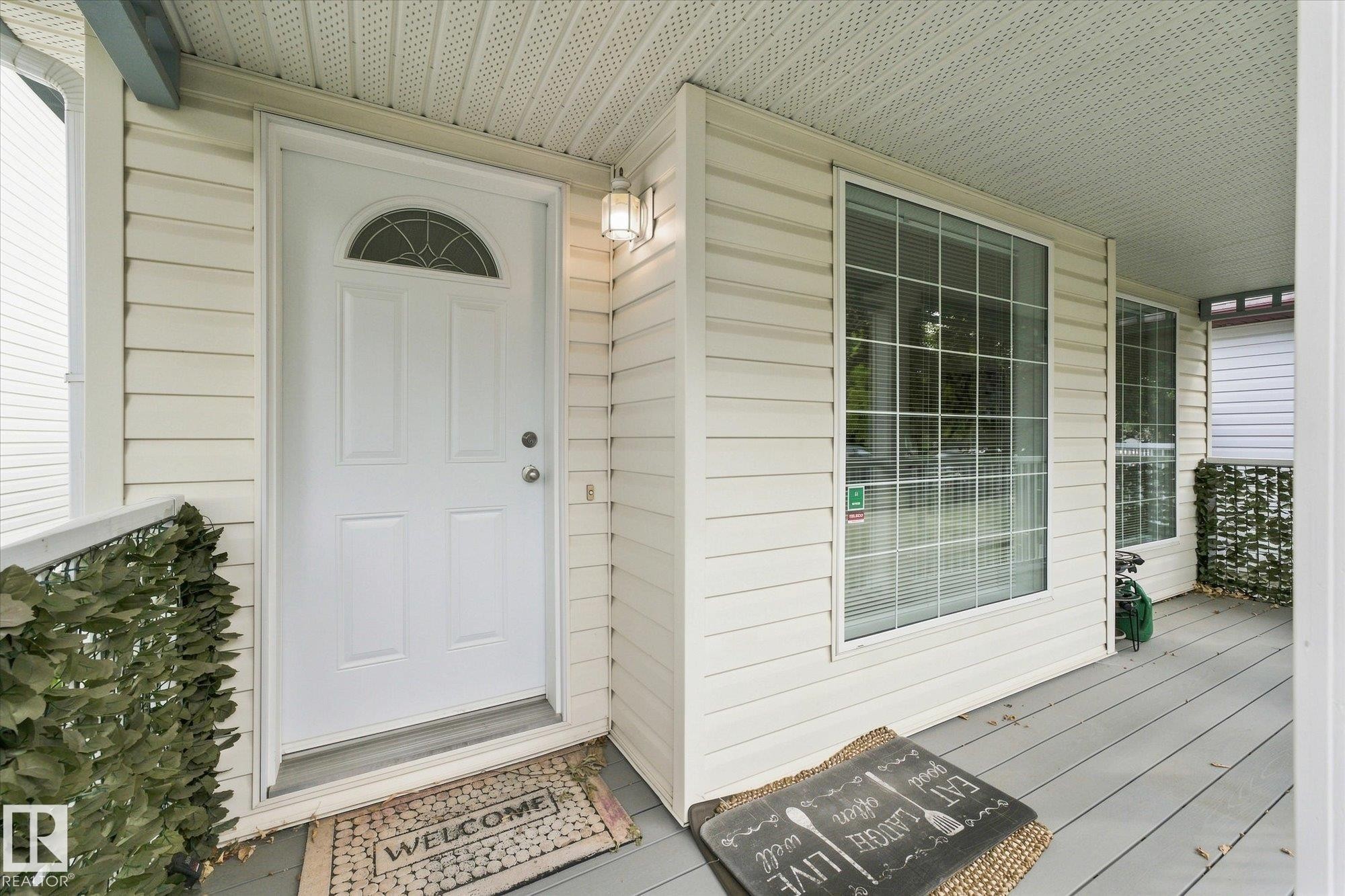 Front entry featuring a paneled door with an arched transom, a sconce light fixture, and horizontal siding - 1709 Turvey Bend Bend Nw, Edmonton, AB