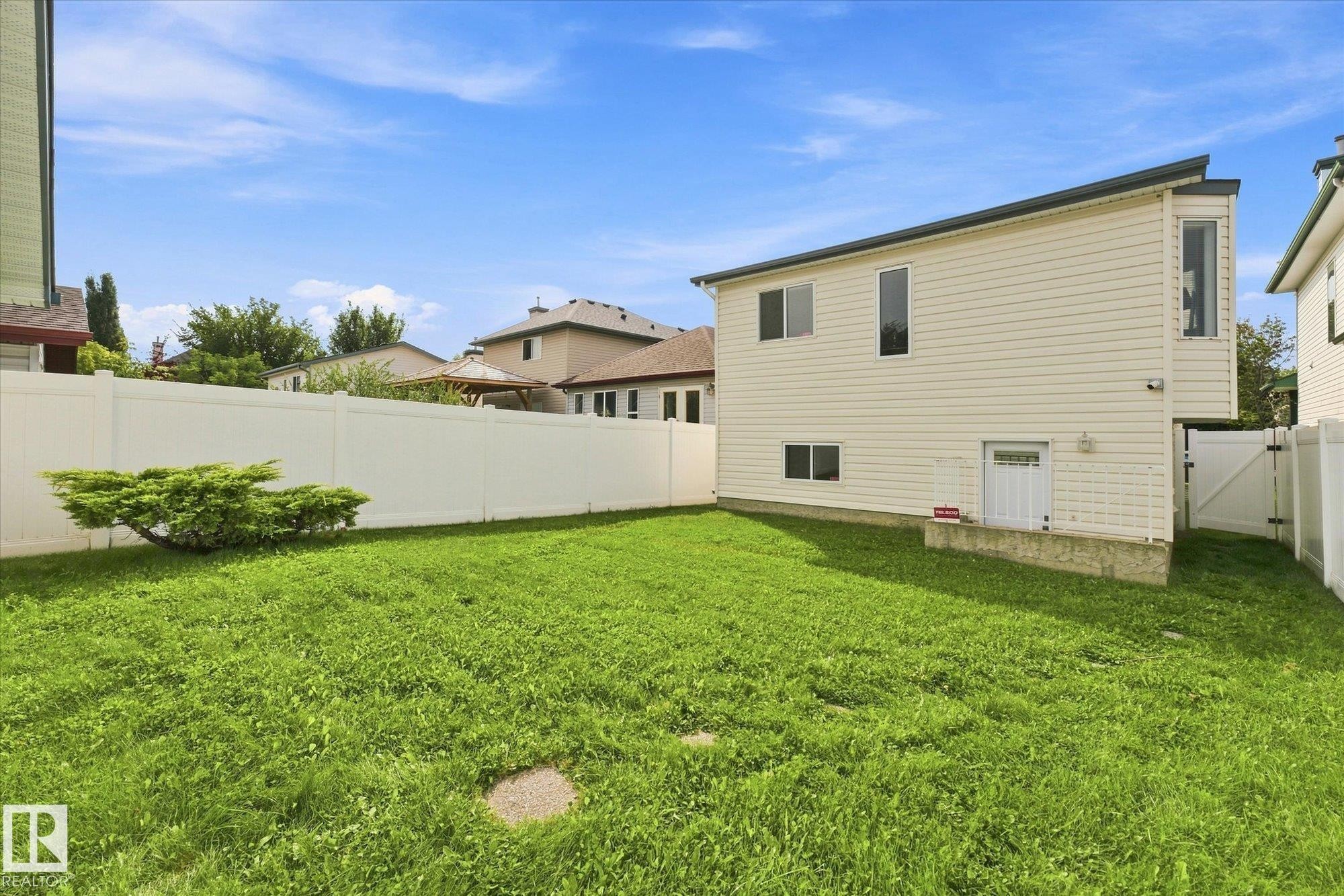 Expansive lawn area, durable vinyl fencing, bay window feature, multiple windows, and a lower-level entry - 1709 Turvey Bend Bend Nw, Edmonton, AB