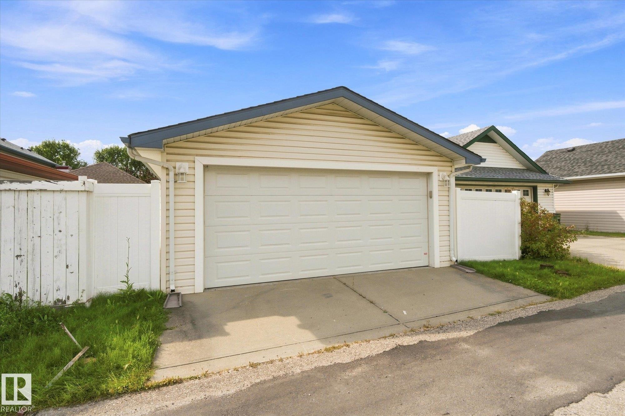 Attached two-car garage with a panel door, vinyl siding, and a dark shingle roof - 1709 Turvey Bend Bend Nw, Edmonton, AB