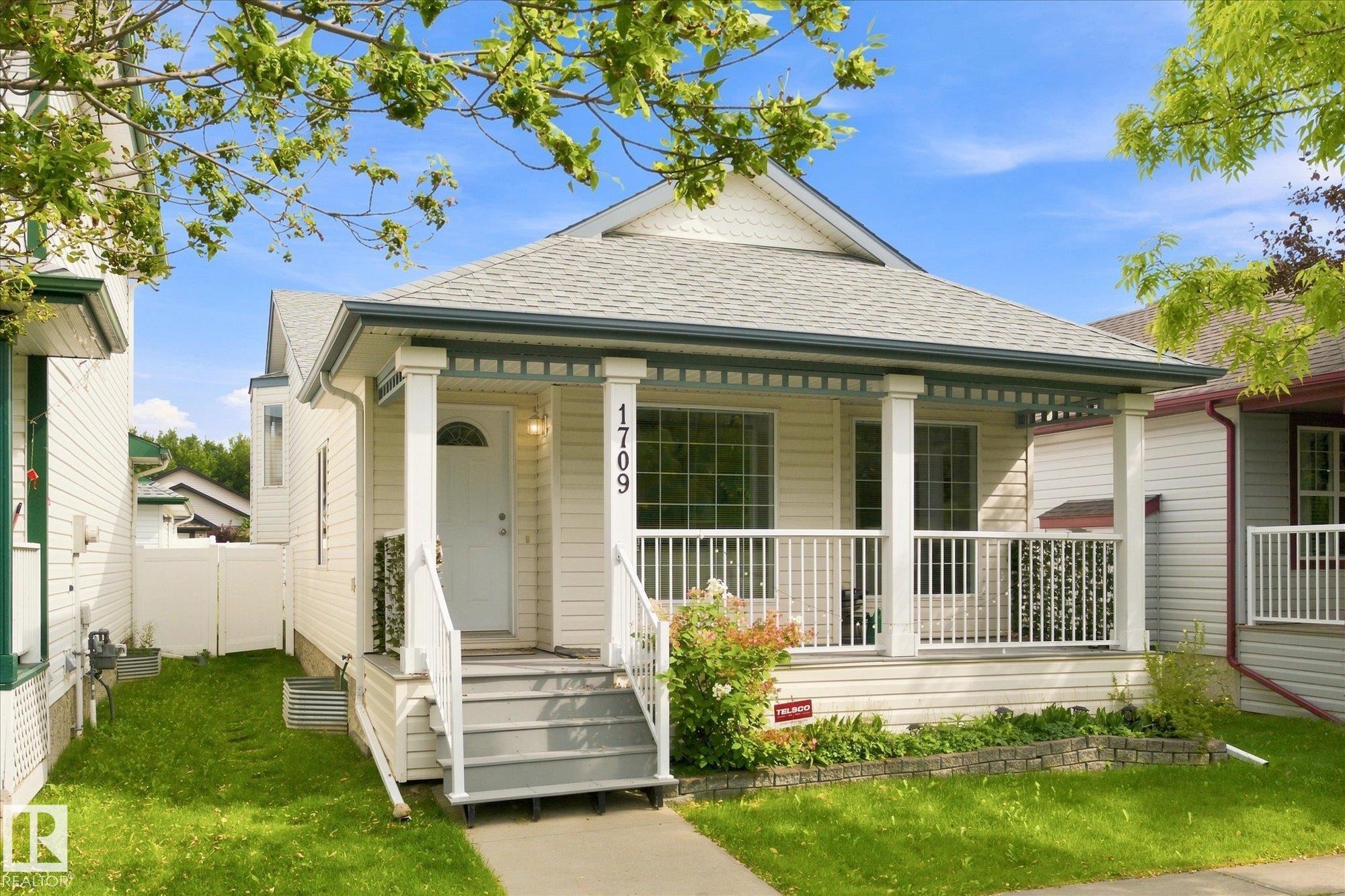Gable roofline, covered front porch, white siding exterior, white railing, and exterior address numbers - 1709 Turvey Bend Bend Nw, Edmonton, AB
