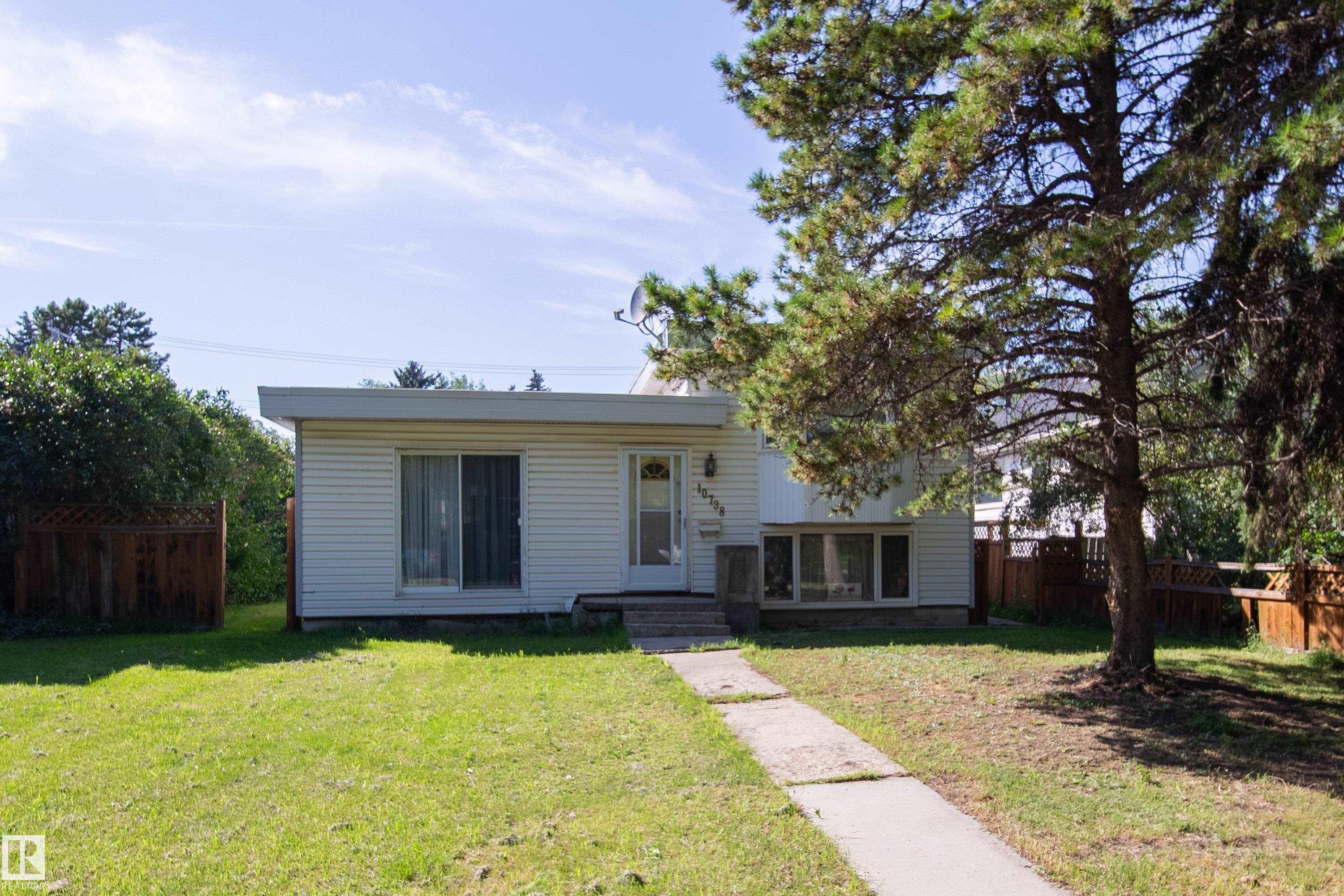 Front facade featuring horizontal siding, a flat roofline, and multiple windows - 10738 129 Street Nw, Edmonton, AB