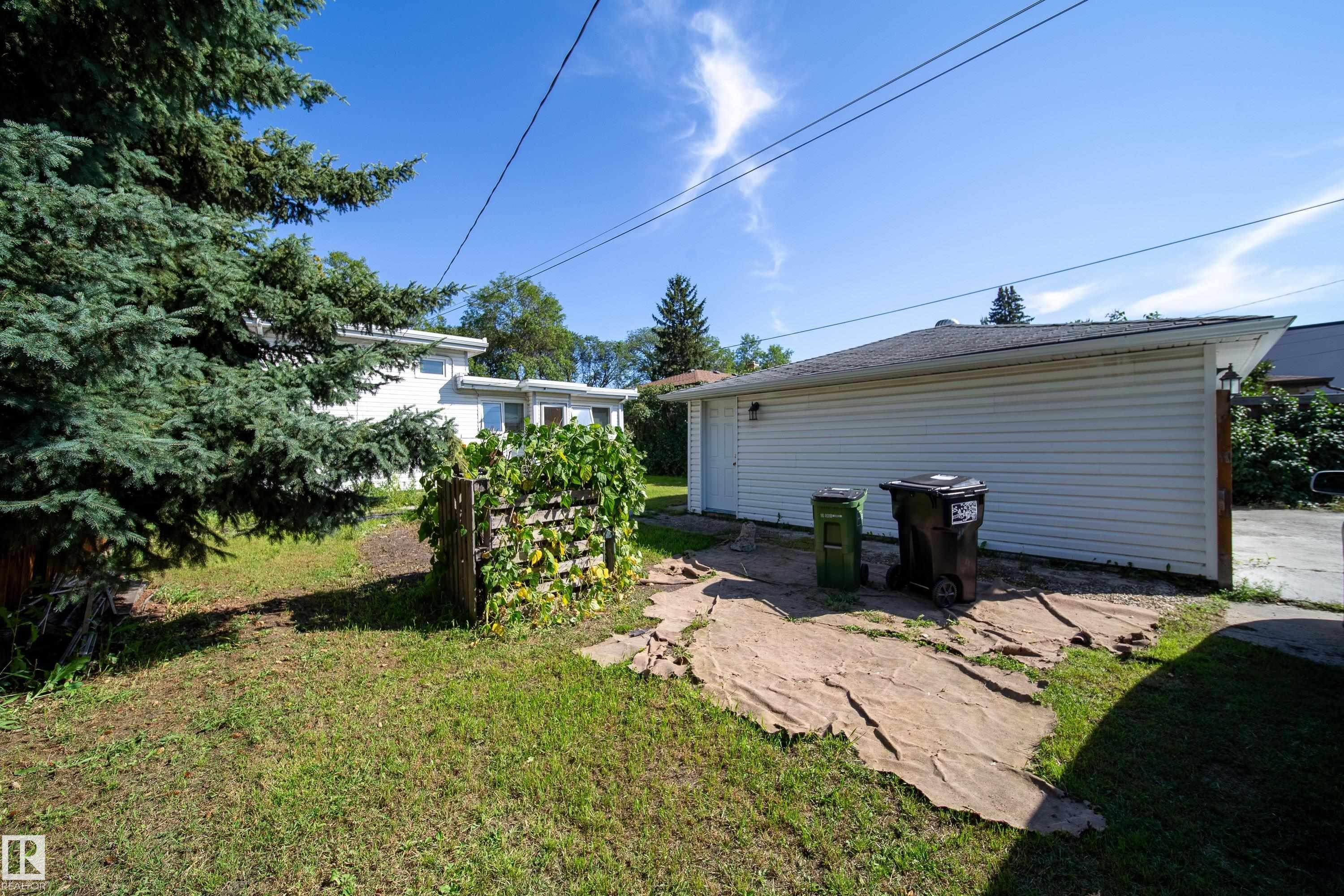 Detached garage with white siding, asphalt shingle roof, and a side access door - 10738 129 Street Nw, Edmonton, AB