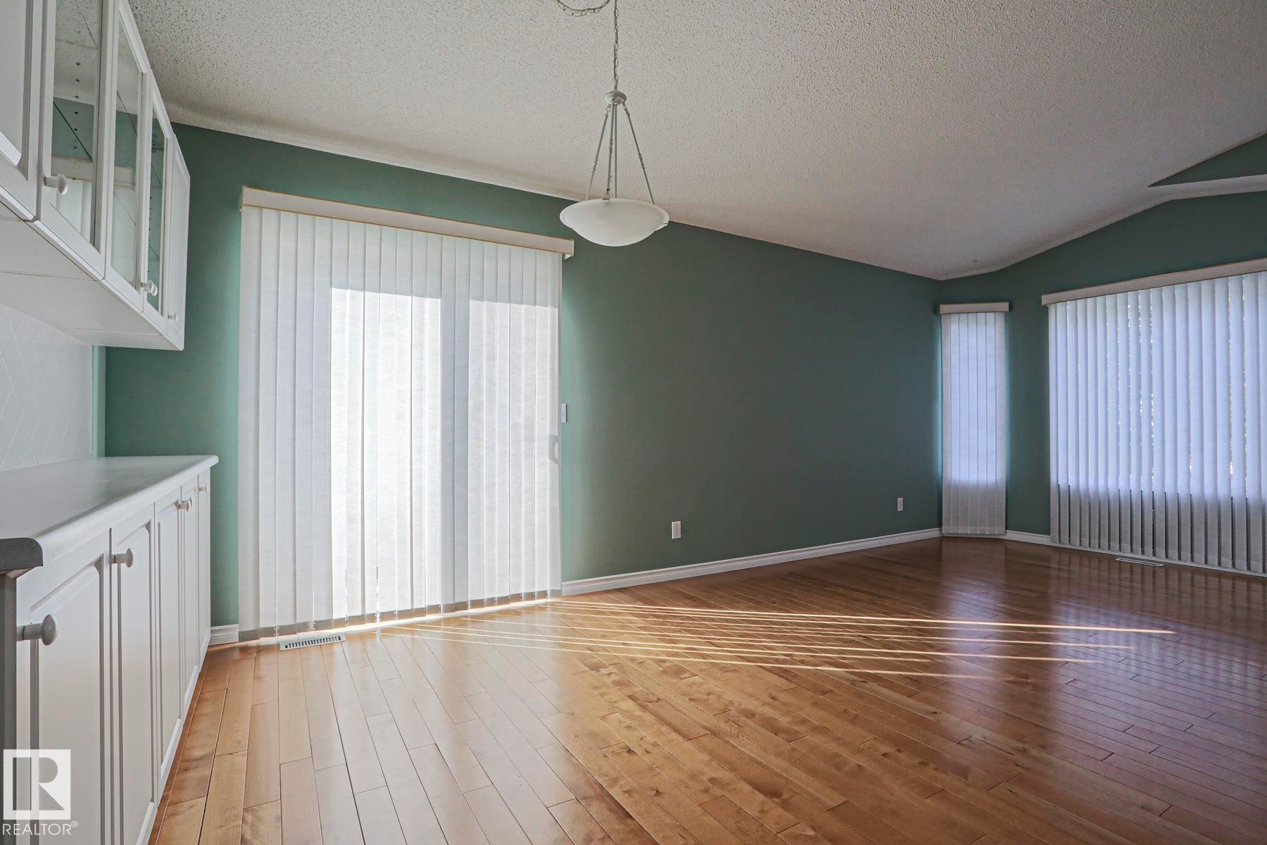 Hardwood flooring, built-in cabinetry with glass-front uppers, track lighting fixture, and vertical blinds - 15031 135 Street Nw, Edmonton, AB