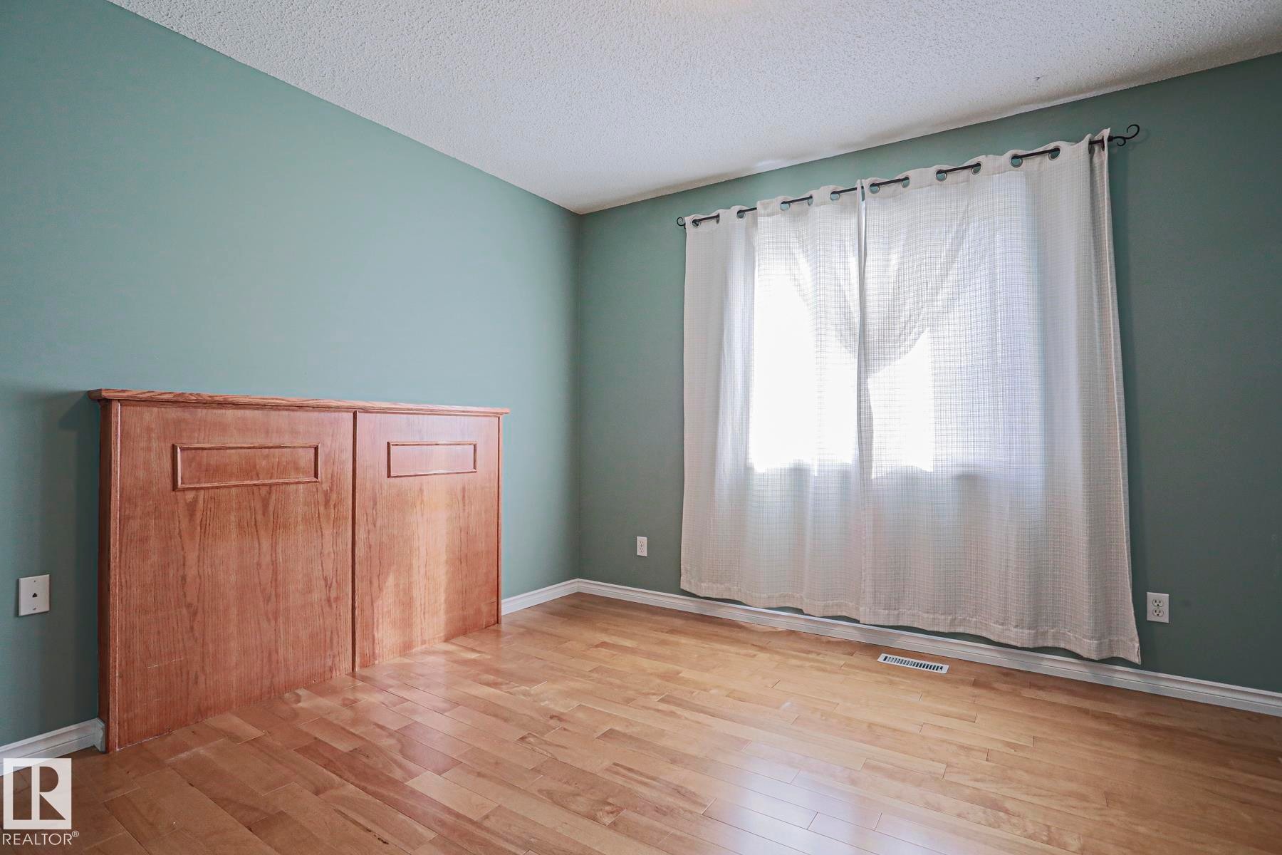 Wood-finish flooring with light-toned wall paint and an expansive window - 15031 135 Street Nw, Edmonton, AB