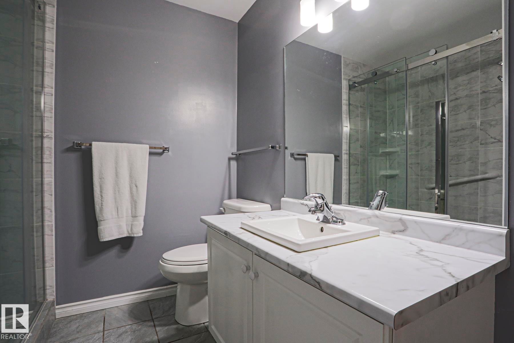 Modern bathroom featuring a white vanity with a rectangular sink, white quartz countertop, polished chrome fixtures, and ample storage - 15031 135 Street Nw, Edmonton, AB