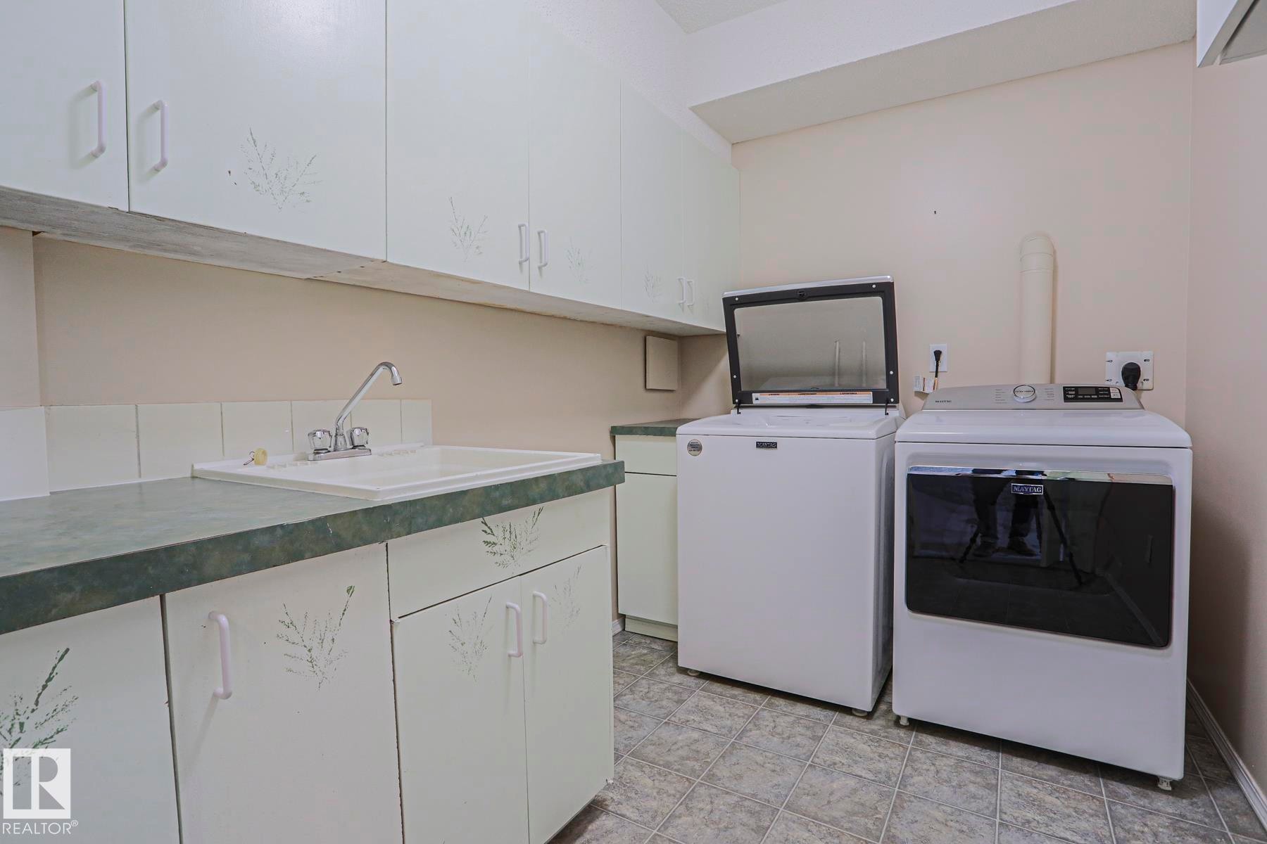White cabinetry with decorative accents, built-in utility sink, and ample countertop space - 15031 135 Street Nw, Edmonton, AB