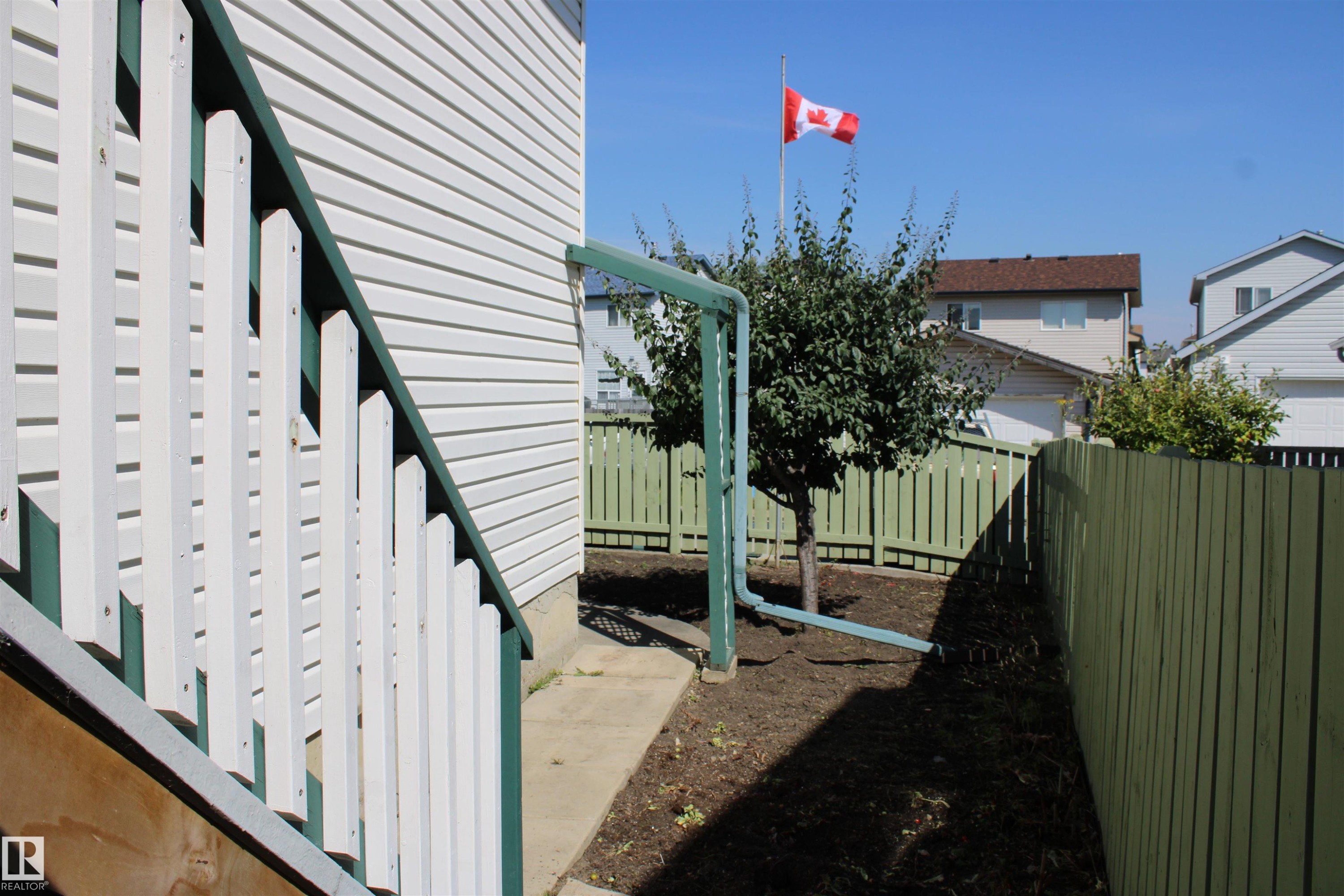 White siding exterior and a painted green wooden fence - 15031 135 Street Nw, Edmonton, AB
