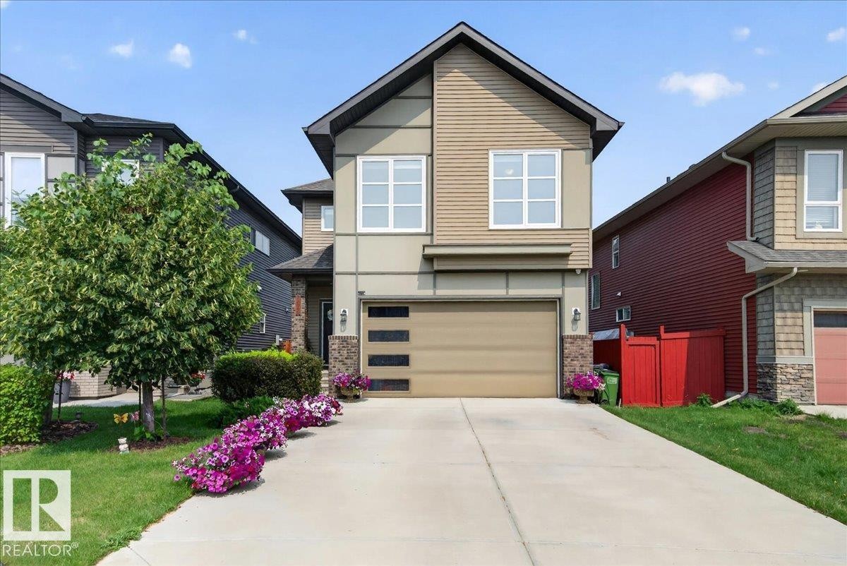 Contemporary two-story residence featuring a combination of siding materials, an integrated garage with modern frosted glass panels, and a concrete driveway - 2709 Collins Crescent Sw, Edmonton, AB - Outdoor
