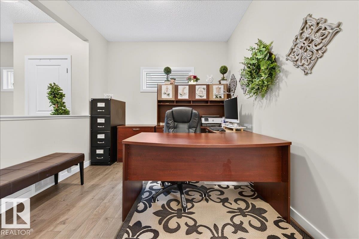 Dedicated office space featuring wood-finish flooring, half-wall separation, and natural light from horizontal windows - 2709 Collins Crescent Sw, Edmonton, AB - Indoor Photo Showing Office