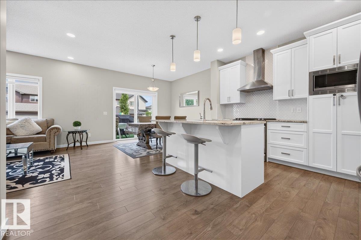 Open-concept kitchen with white cabinetry, stainless steel appliances, and a central island featuring a granite-look countertop - 2709 Collins Crescent Sw, Edmonton, AB - Indoor Photo Showing Kitchen With Upgraded Kitchen
