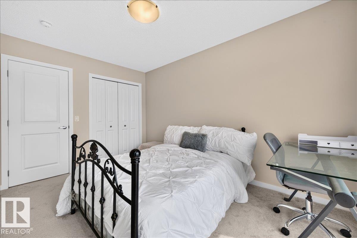 Bedroom featuring neutral wall paint, light-colored carpeting, a ceiling-mounted light fixture, a paneled door, and bi-fold closet doors - 2709 Collins Crescent Sw, Edmonton, AB - Indoor Photo Showing Bedroom