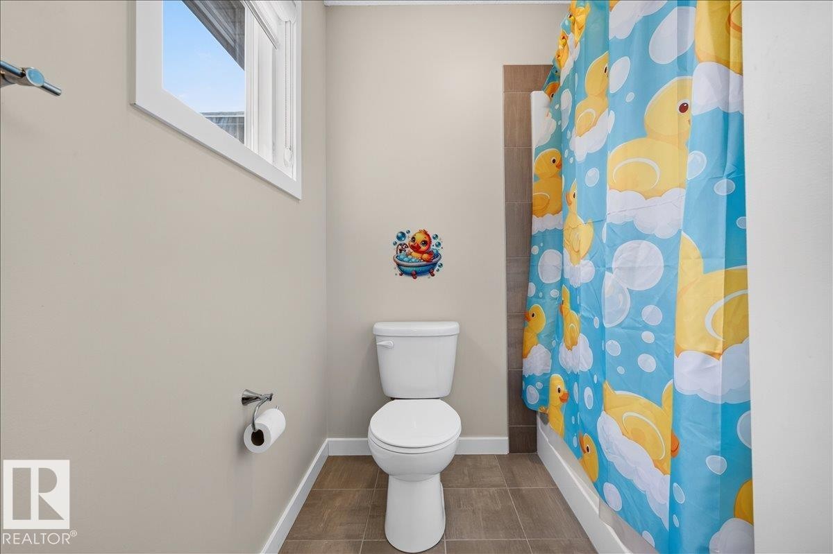 Bathroom featuring a white toilet, tile flooring, a window with white trim, and a shower with a tiled surround - 2709 Collins Crescent Sw, Edmonton, AB - Indoor Photo Showing Bathroom