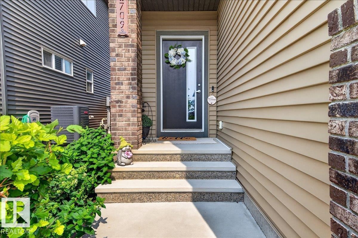 Inviting entry with concrete steps and dark-framed door featuring a decorative glass insert - 2709 Collins Crescent Sw, Edmonton, AB - Outdoor