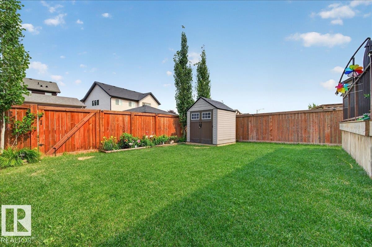 Expansive lawn area featuring a storage shed, full perimeter fencing, mature trees, and a raised garden bed - 2709 Collins Crescent Sw, Edmonton, AB - Outdoor