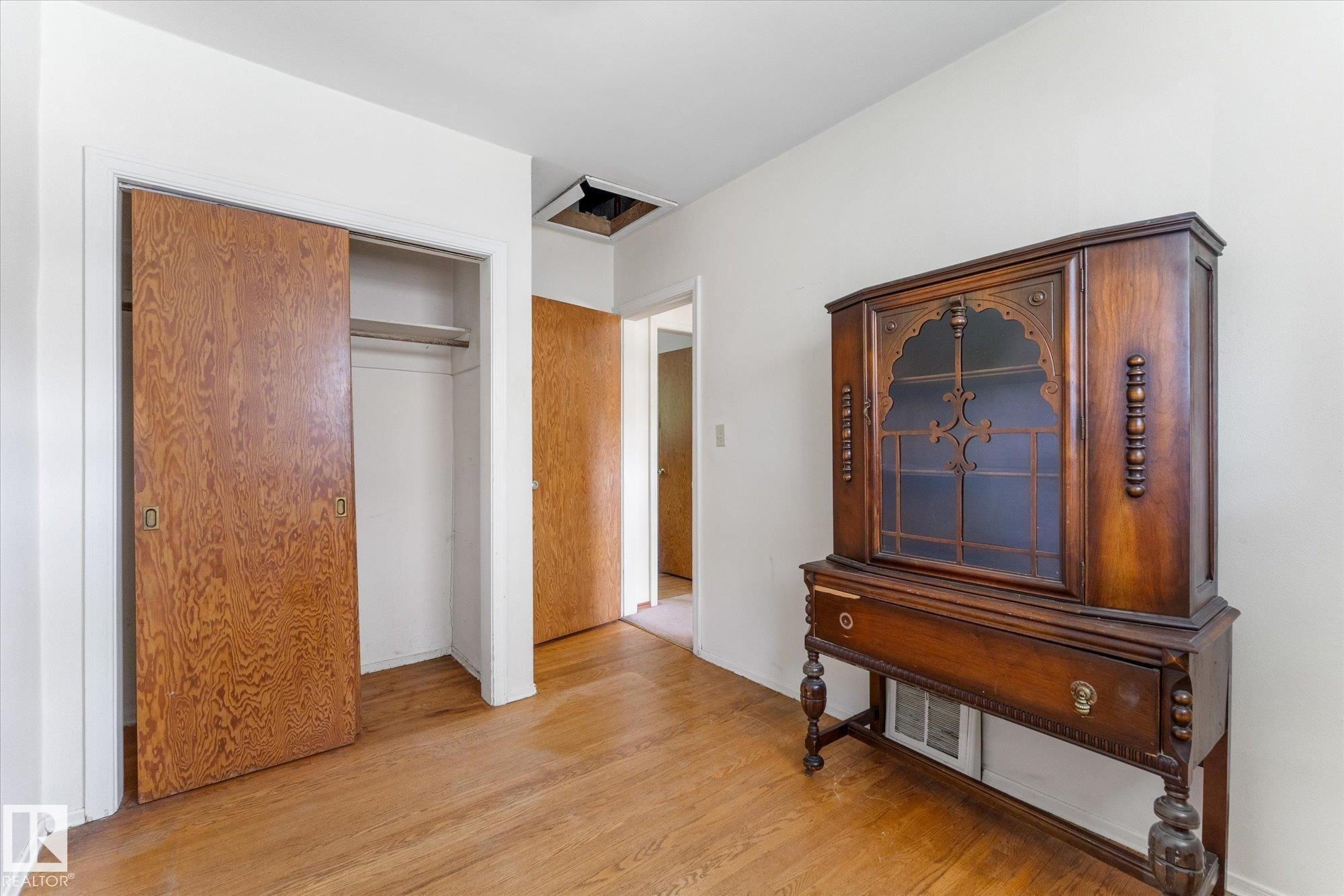 Wood-finish flooring with white walls and a built-in closet featuring bi-fold doors - 9315 86 Street Nw, Edmonton, AB