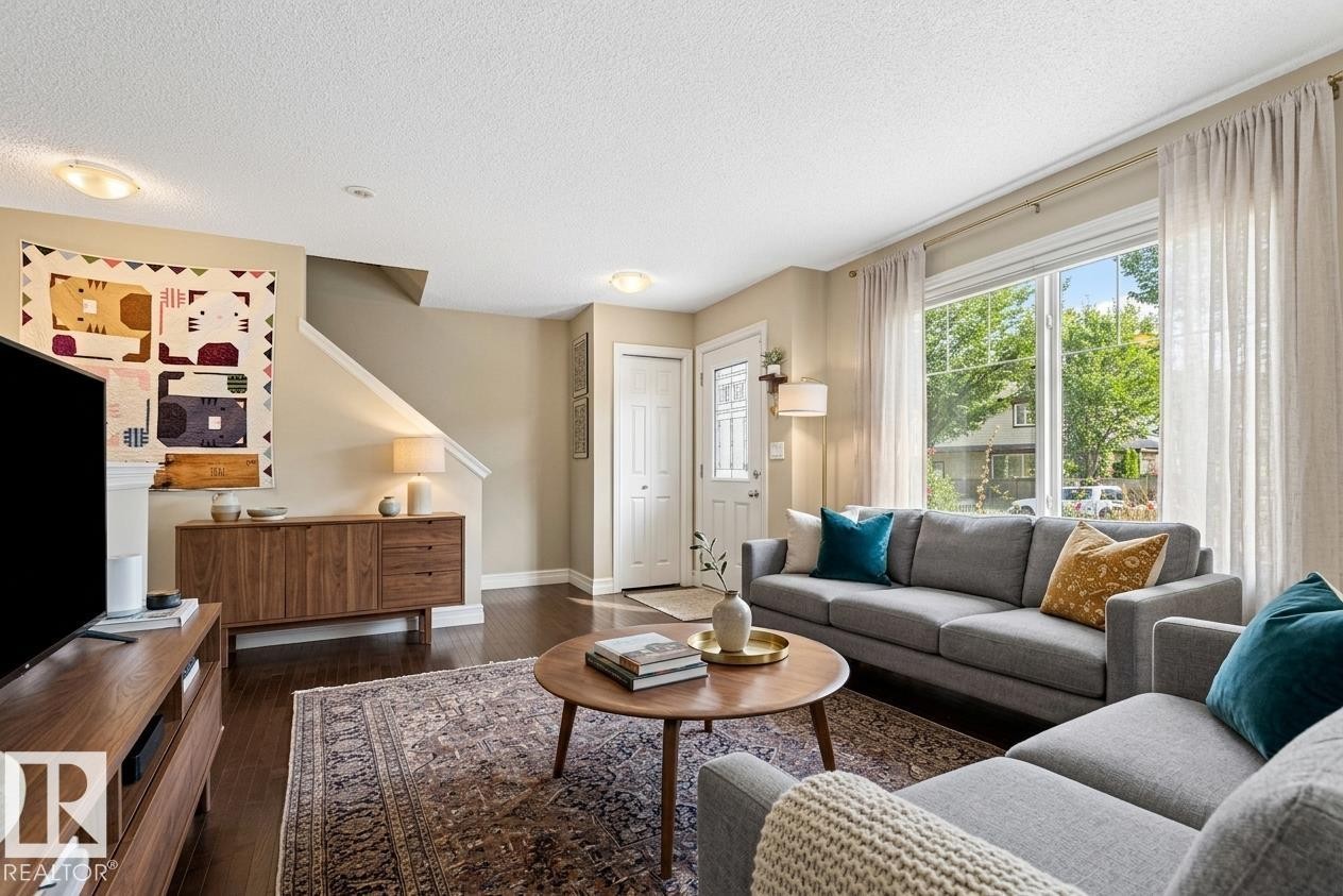 Hardwood-finish flooring, recessed lighting, expansive window with natural light, built-in entryway closet, staircase with white railing - 5319 3 Avenue Sw, Edmonton, AB